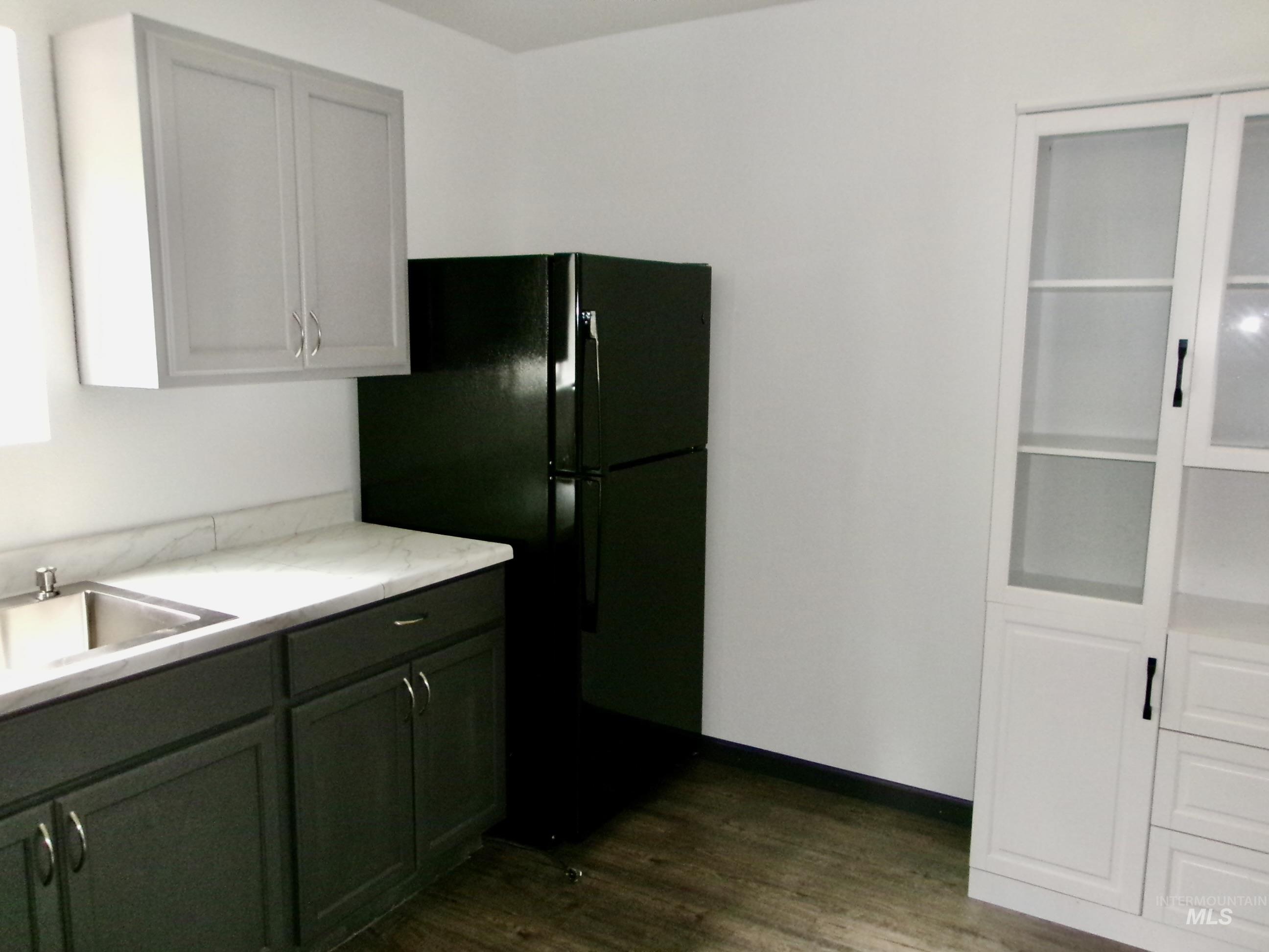 Kitchen with freestanding refrigerator, dark wood-type flooring, and green cabinetry