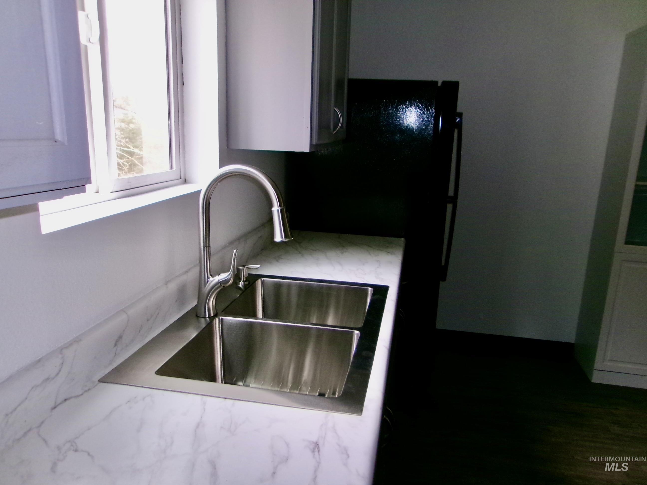 Kitchen view of light stone countertops and freestanding refrigerator