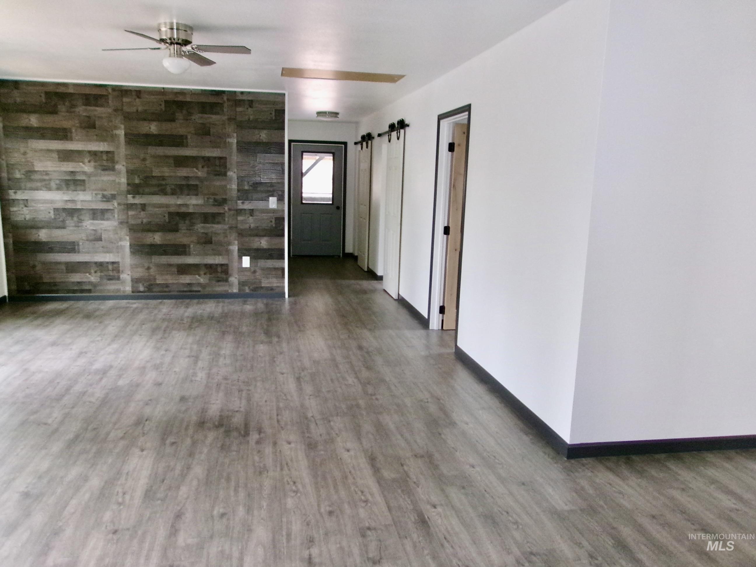 Spare room featuring wood finished floors, ceiling fan, and a barn door