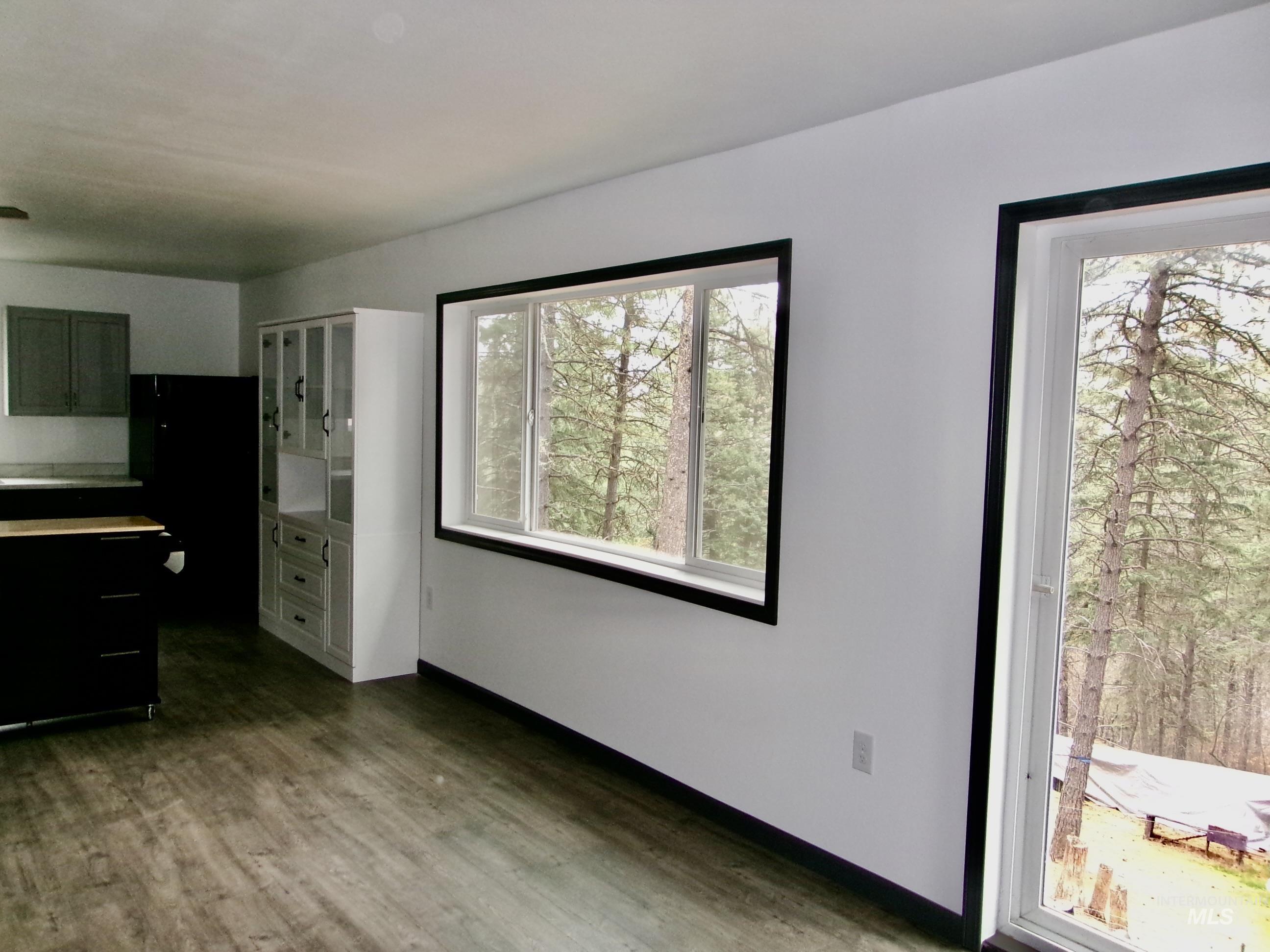 Unfurnished dining area featuring dark wood finished floors and baseboards