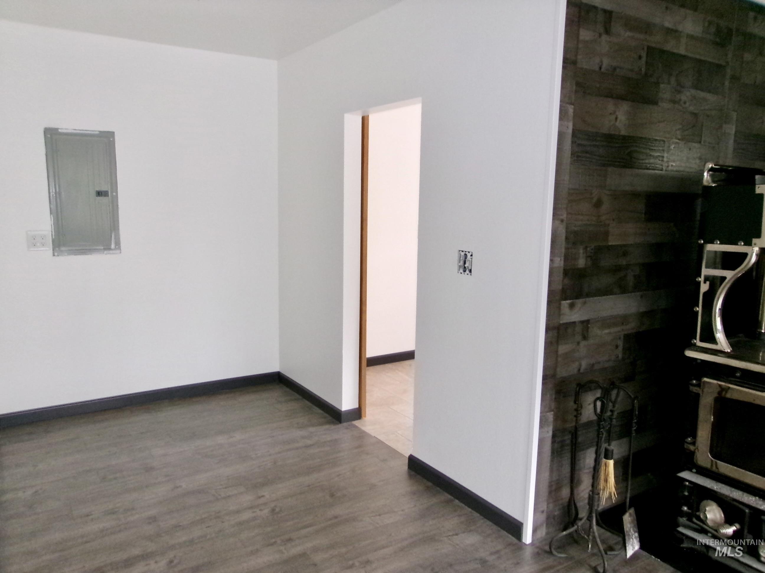 Empty room with electric panel and dark wood-style floors