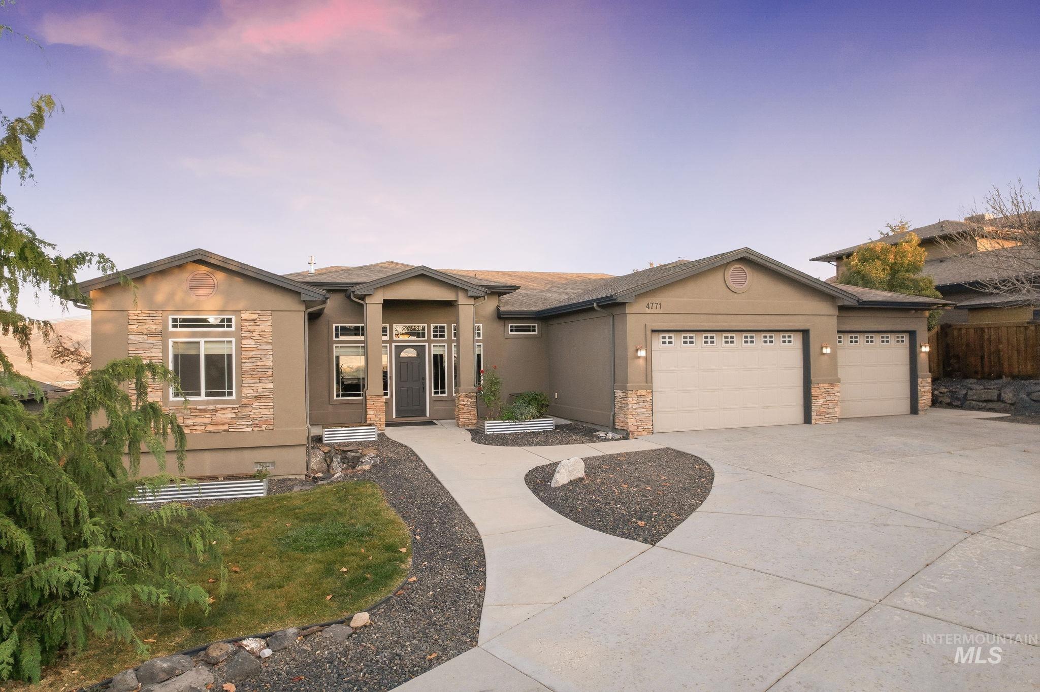 View of front facade featuring stone siding, stucco siding, driveway, and a garage