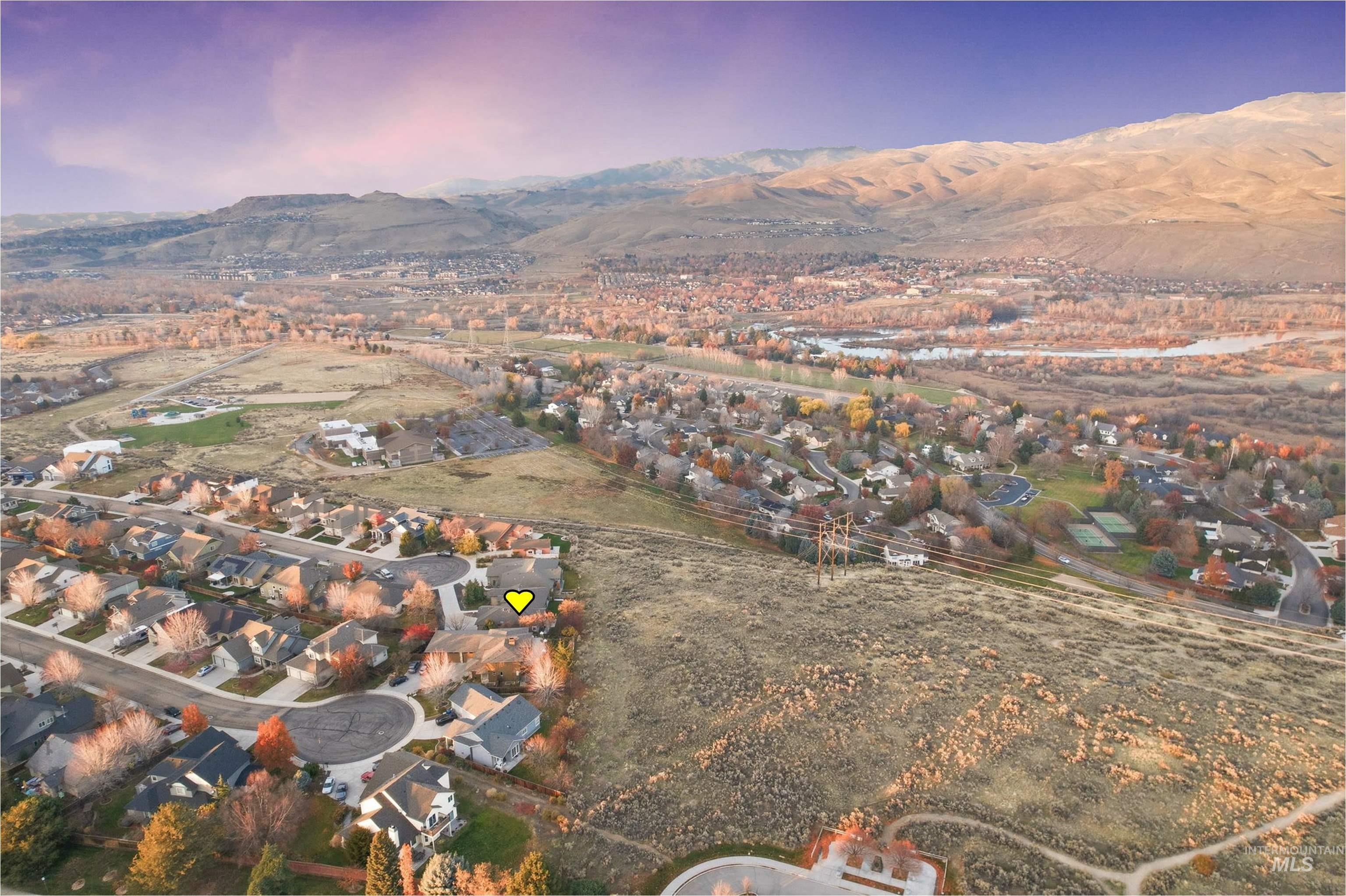 Aerial view of property and surrounding area featuring nearby suburban area and a mountainous background
