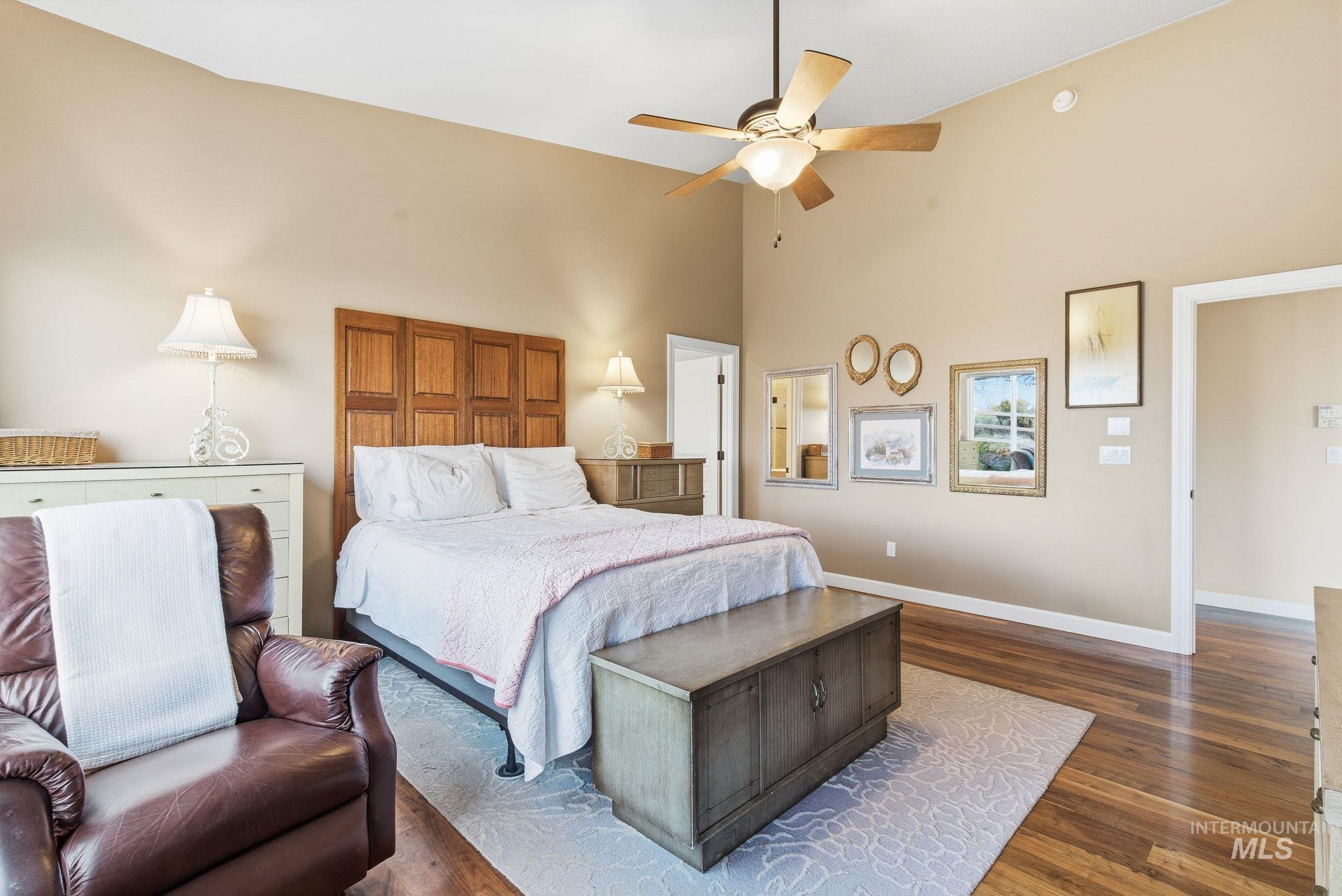 Bedroom featuring high vaulted ceiling, wood finished floors, and a ceiling fan