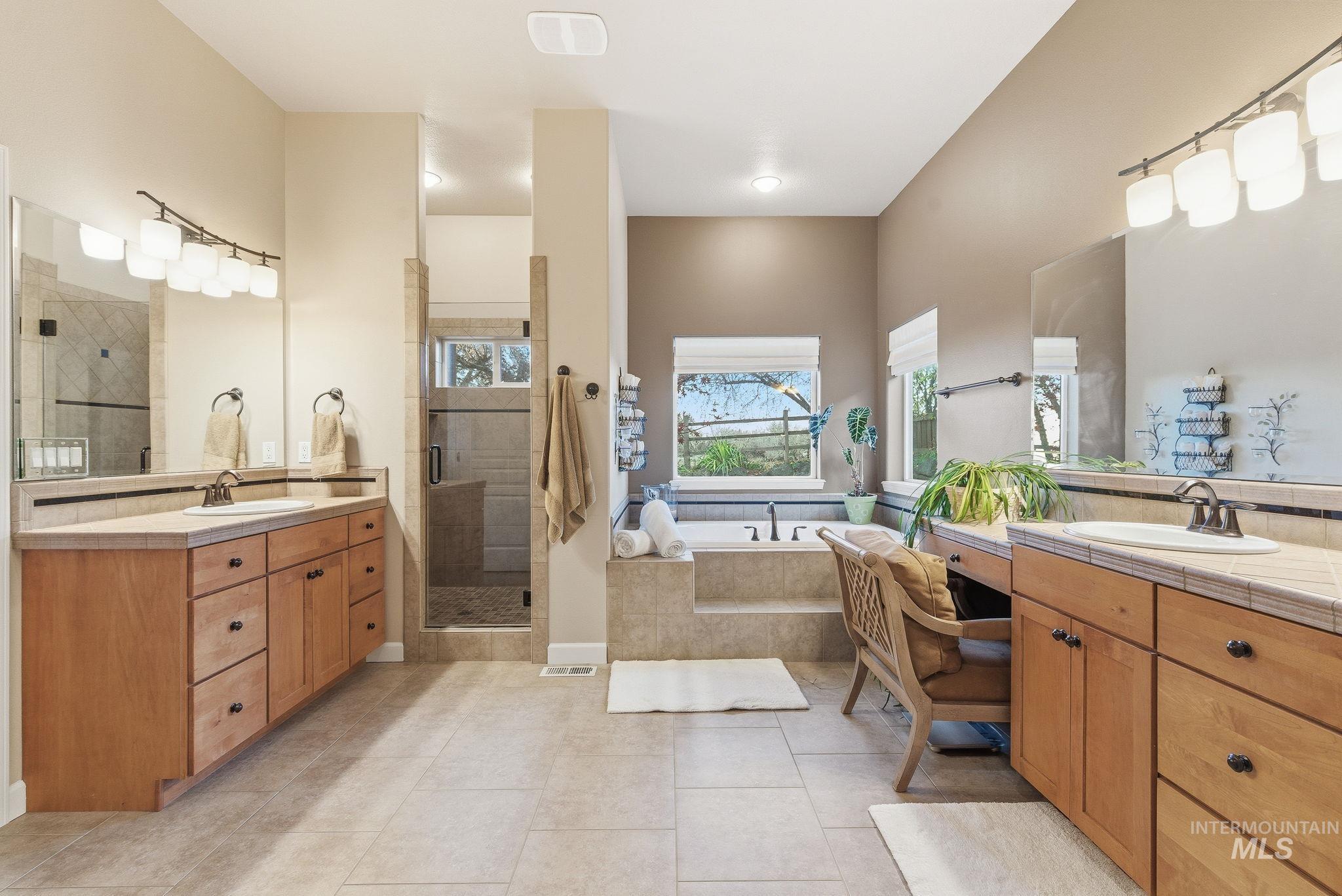Bathroom with two vanities, a garden tub, a stall shower, and light tile patterned floors