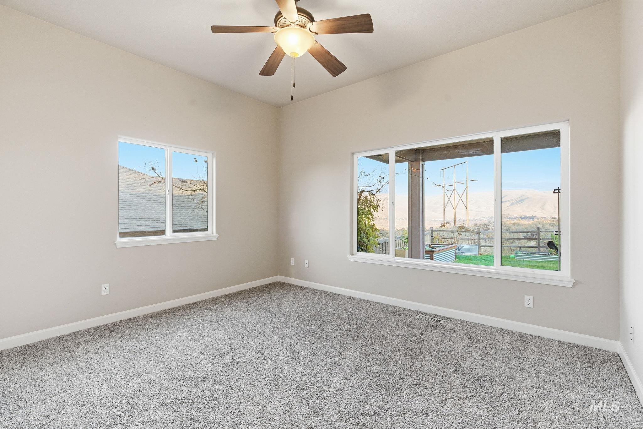 Empty room with carpet floors and ceiling fan