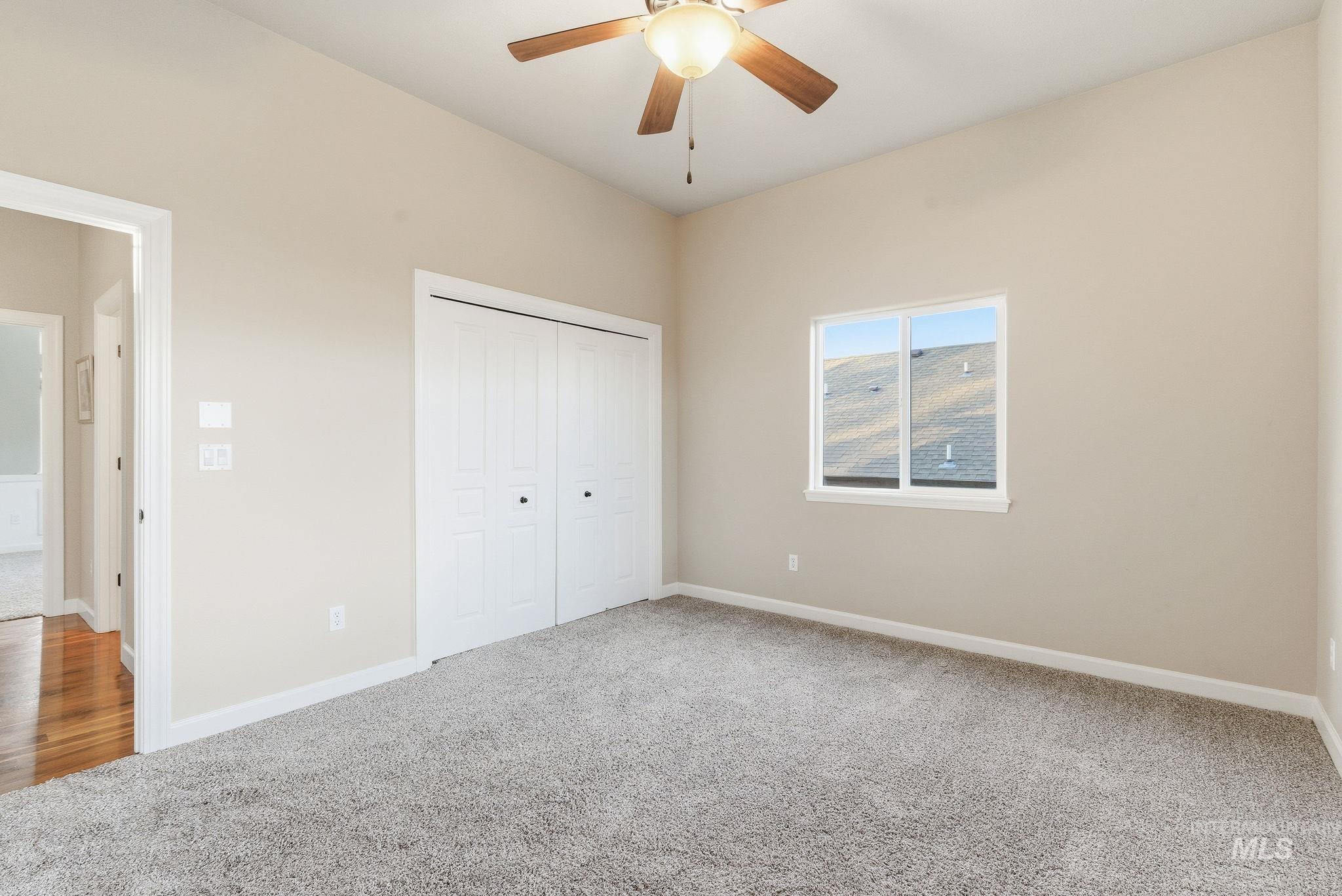 Unfurnished bedroom with light carpet, a closet, and a ceiling fan