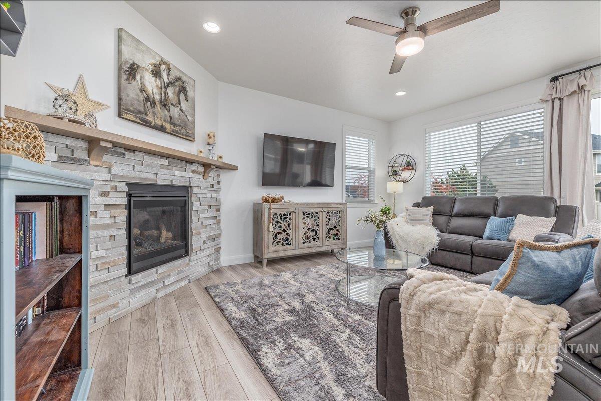 Living area featuring a stone fireplace, light wood-style flooring, recessed lighting, and ceiling fan