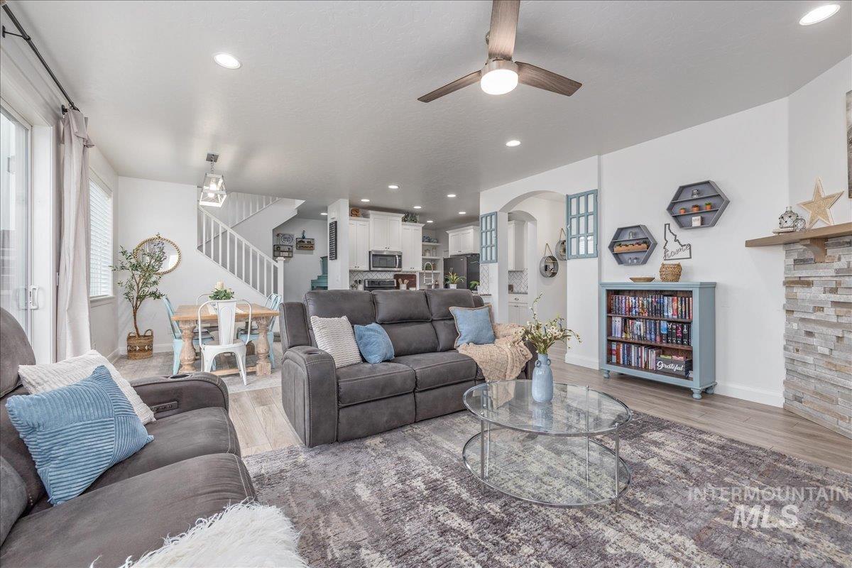 Living area with stairway, recessed lighting, wood finished floors, arched walkways, and ceiling fan