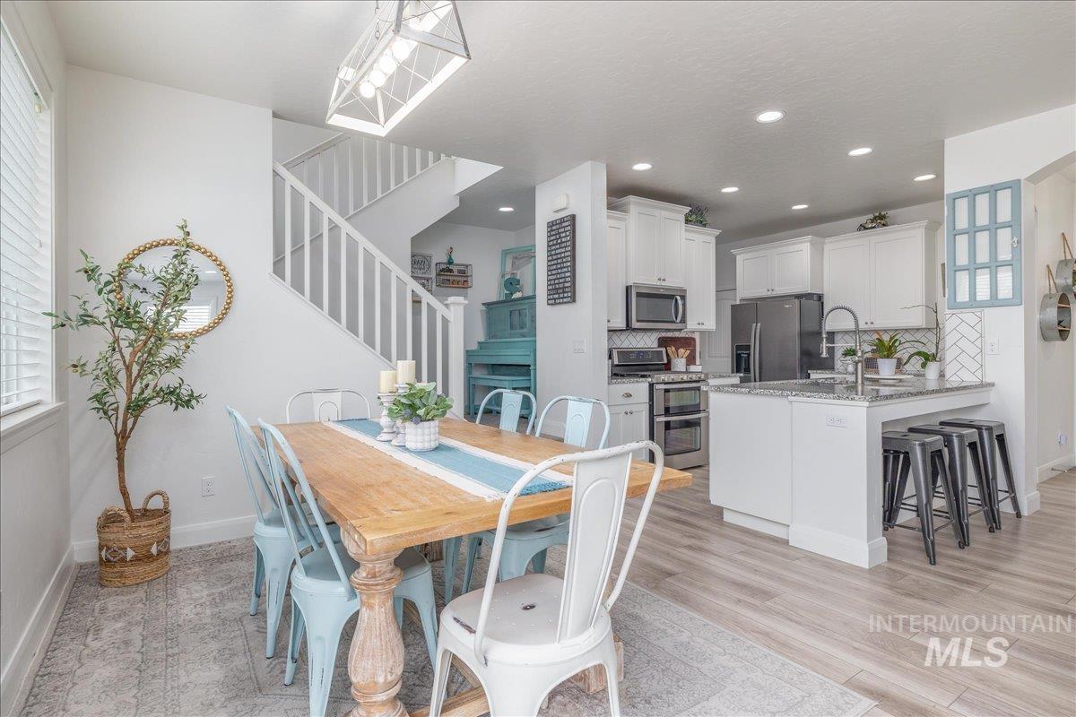 Dining area with stairway and light wood-style floors