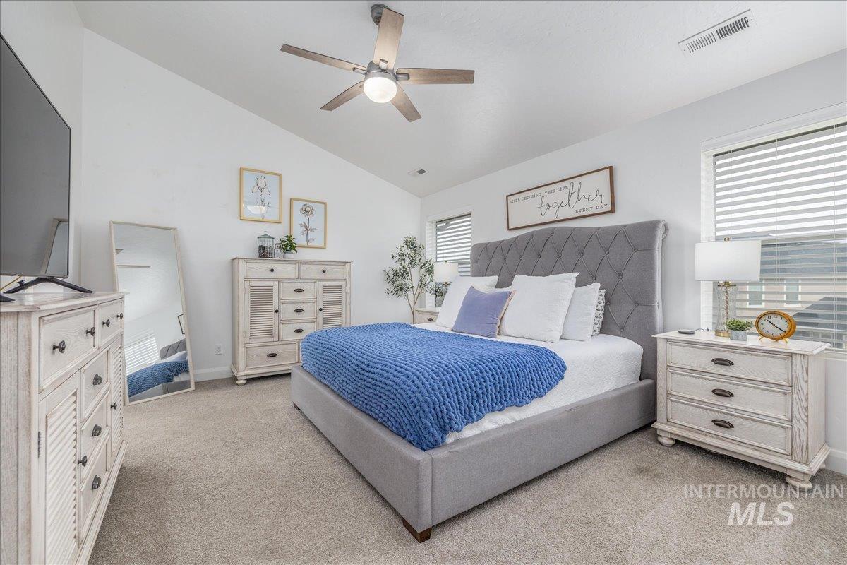 Bedroom with vaulted ceiling, light carpet, and ceiling fan