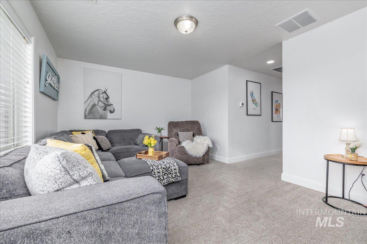 Living area featuring carpet and a textured ceiling