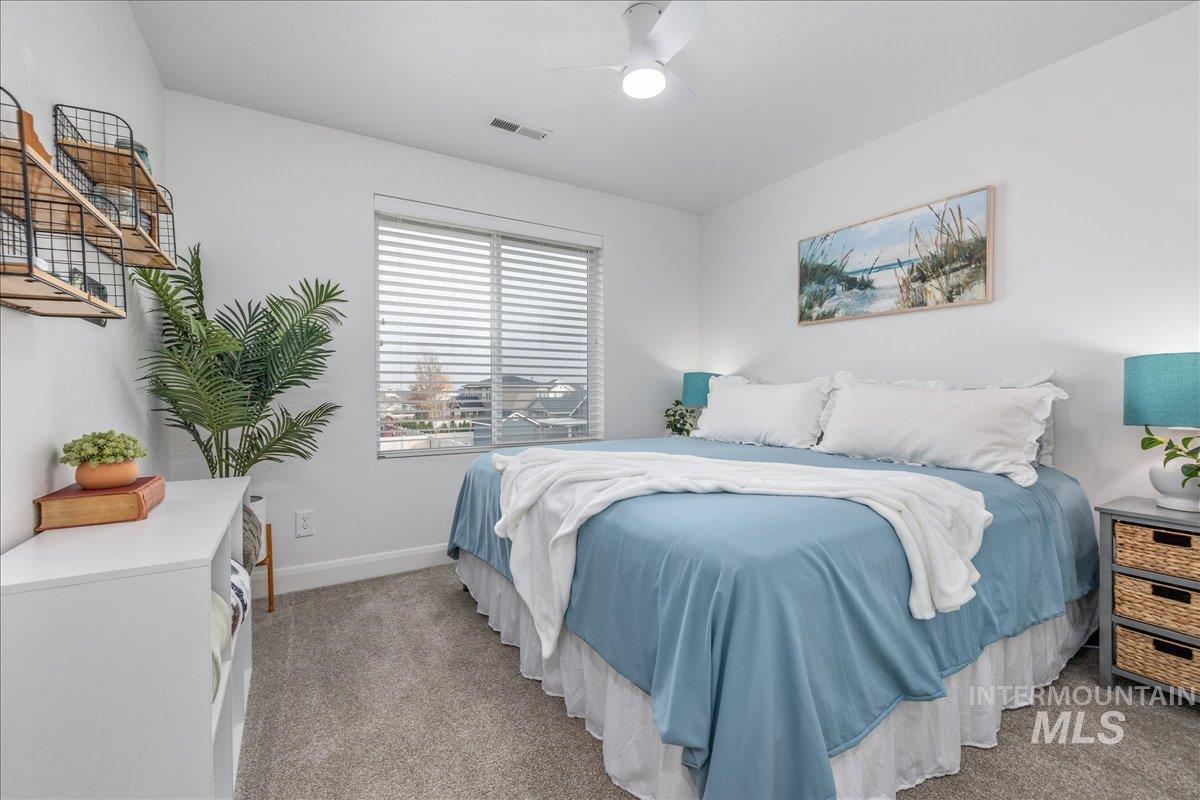 Bedroom with light colored carpet and a ceiling fan