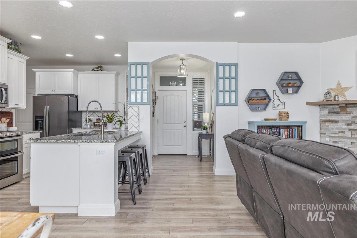 Kitchen featuring appliances with stainless steel finishes, a breakfast bar, tasteful backsplash, white cabinetry, and recessed lighting