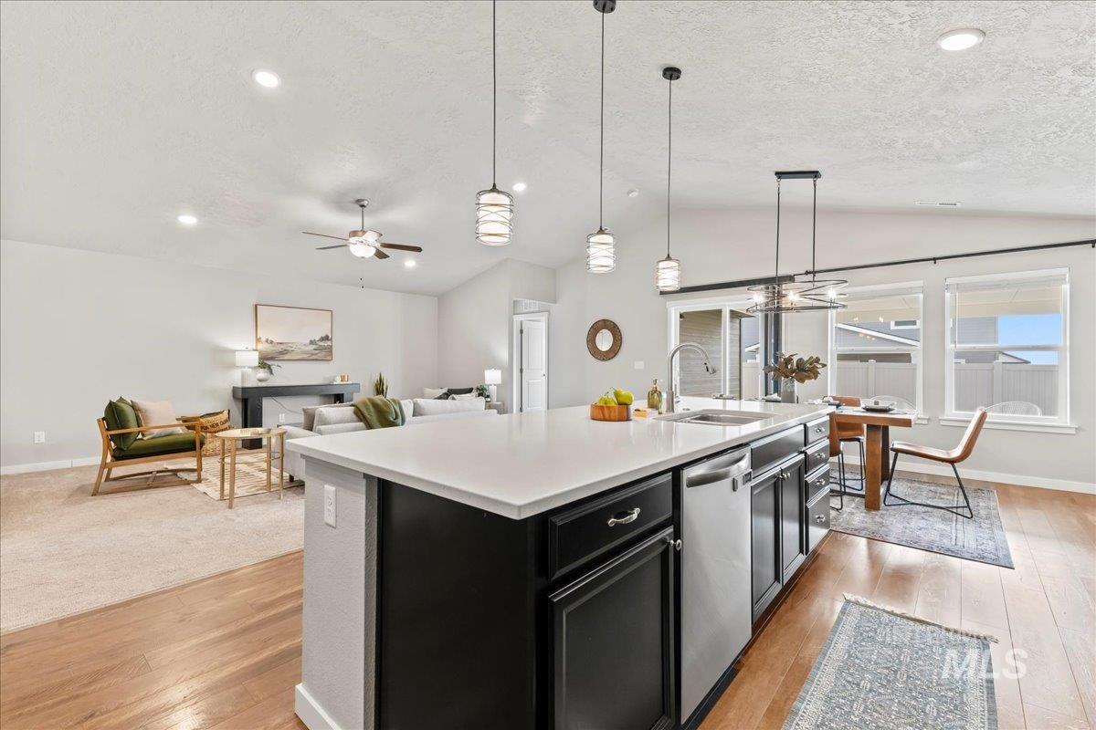 Kitchen with dark cabinets, pendant lighting, lofted ceiling, light wood-type flooring, and ceiling fan