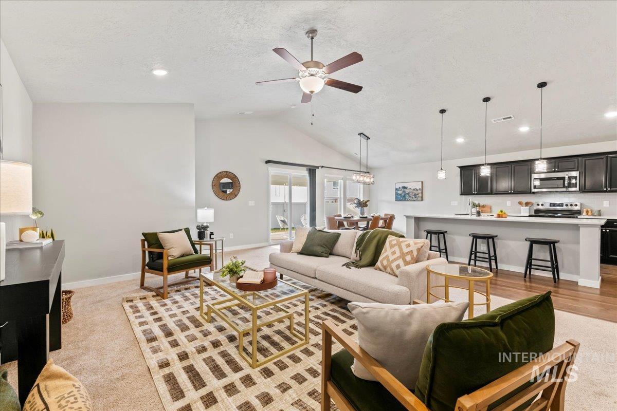 Living room with a textured ceiling, ceiling fan, lofted ceiling, and recessed lighting