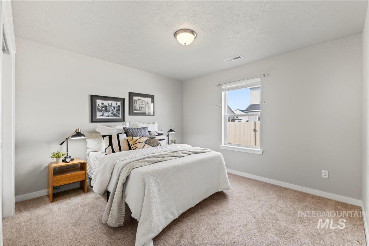 Bedroom featuring light colored carpet and a textured ceiling