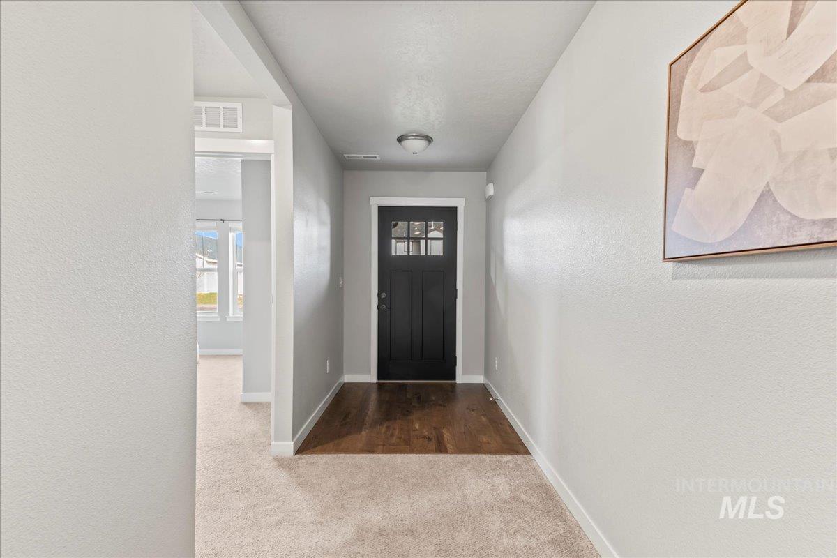 Foyer entrance with dark colored carpet and a textured wall