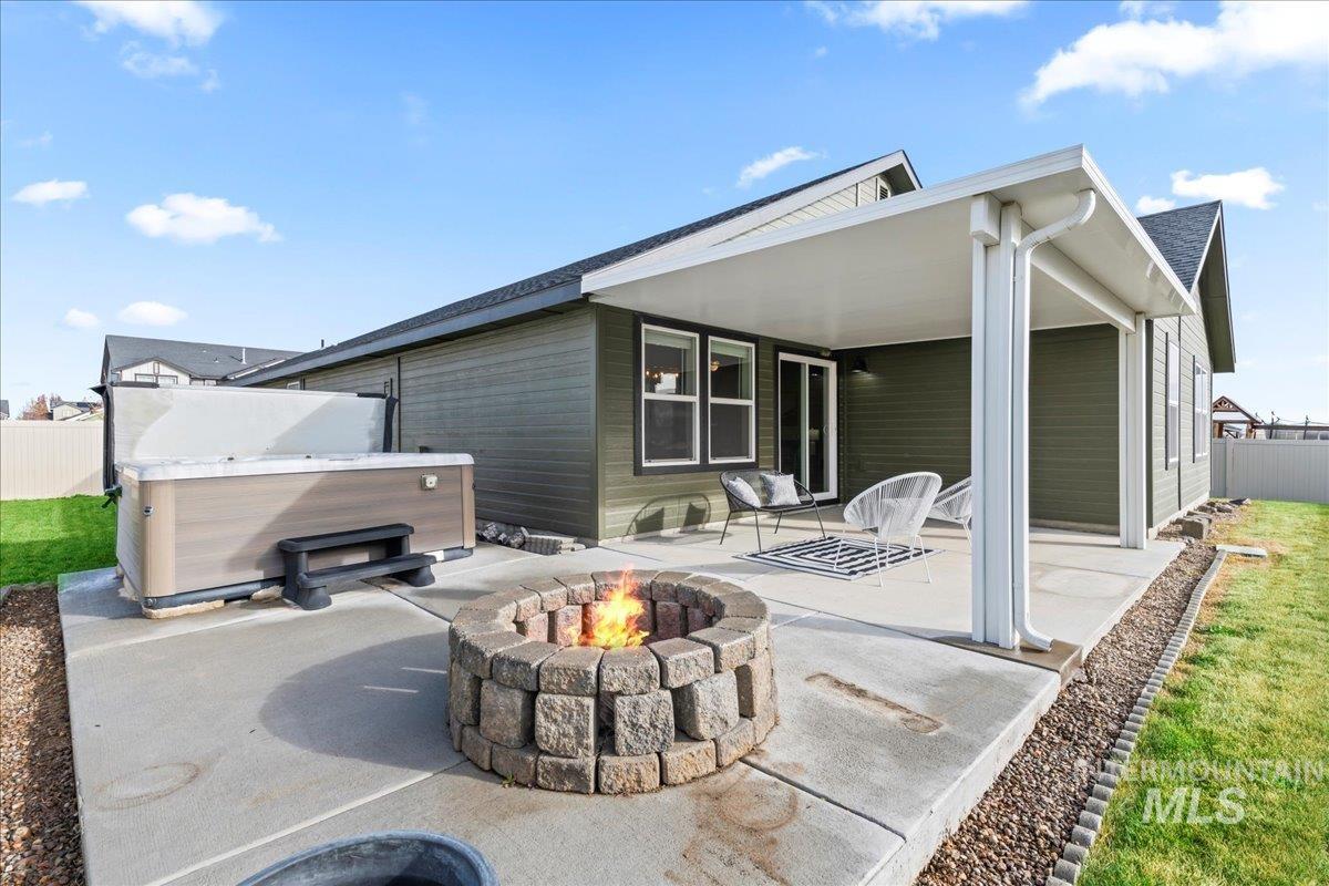 Back of property featuring a patio, a hot tub, and an outdoor fire pit