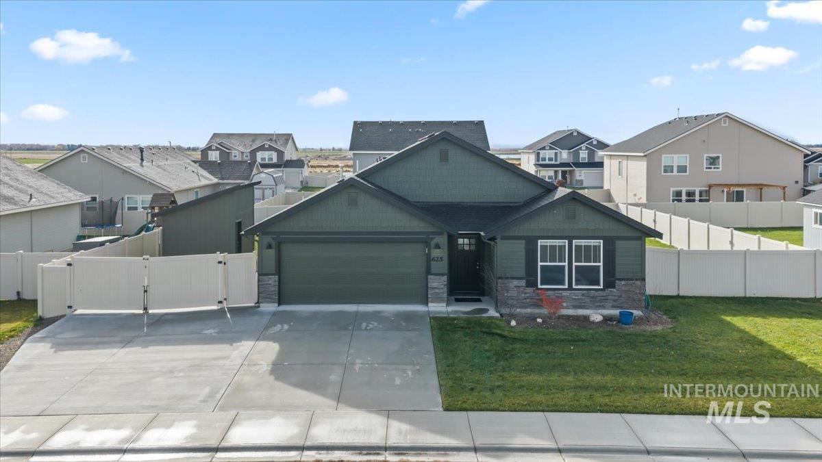 Craftsman-style home featuring stone siding, a residential view, driveway, a garage, and a gate