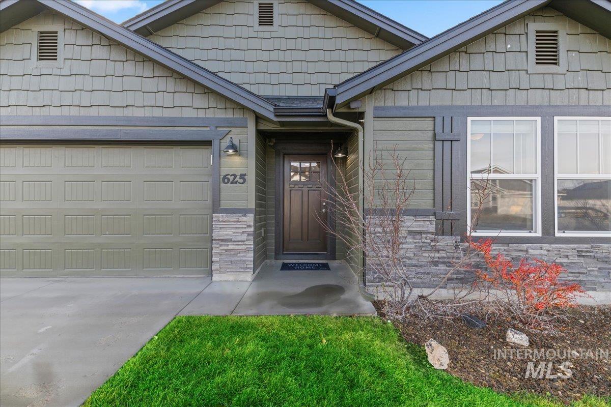 View of front of house with stone siding, an attached garage, and driveway