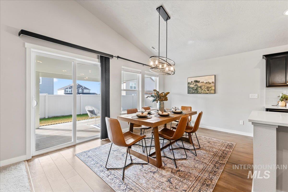Dining space featuring lofted ceiling, light wood-style flooring, a chandelier, and a textured ceiling