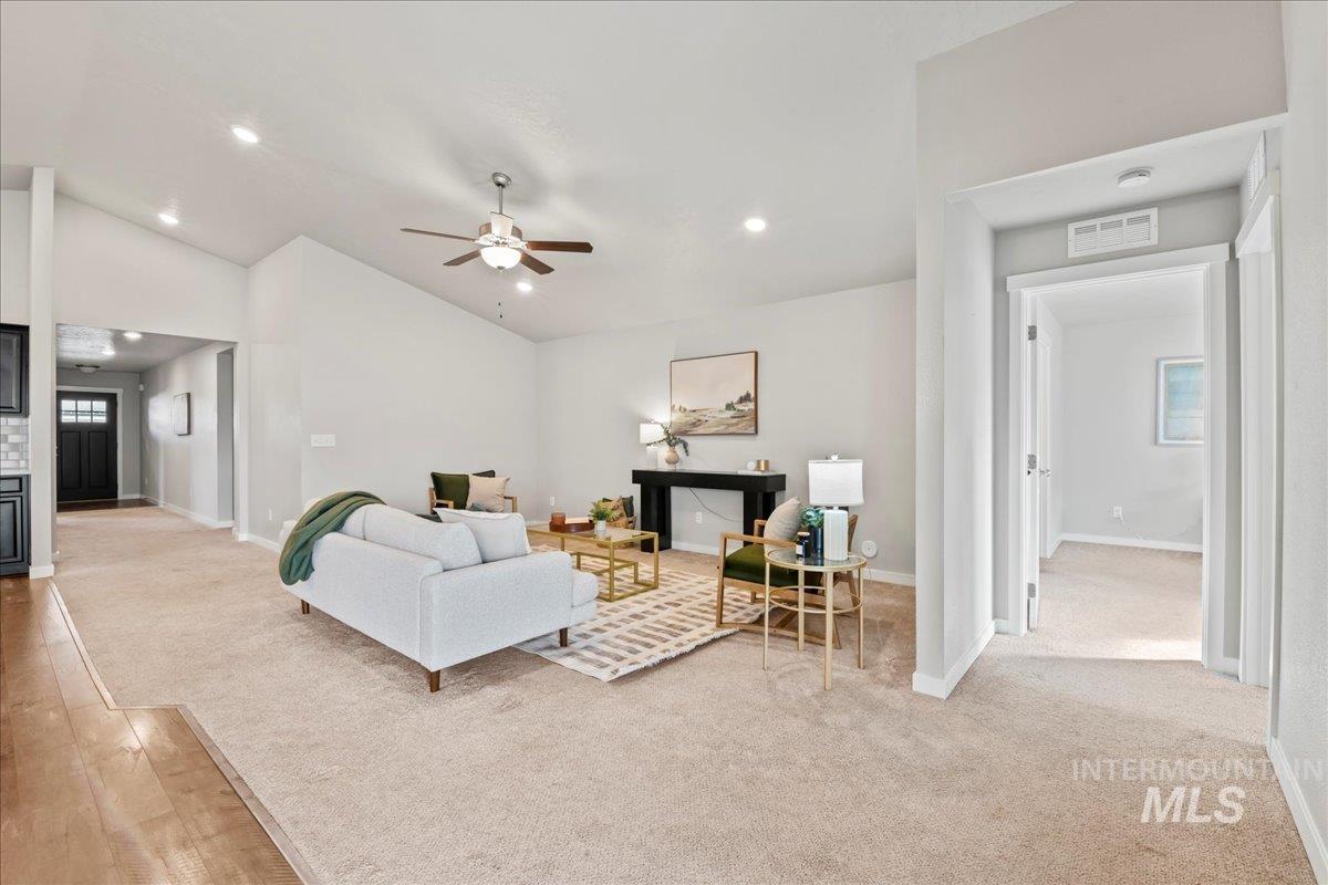 Living room featuring light carpet, a fireplace, a ceiling fan, vaulted ceiling, and recessed lighting