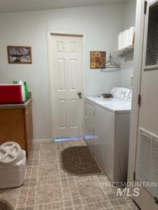 Washroom with independent washer and dryer, a heating unit, and light tile patterned floors