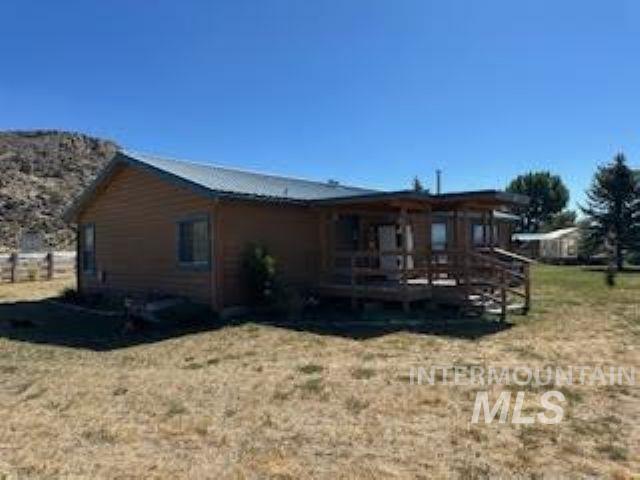 Rear view of property featuring a lawn and a deck