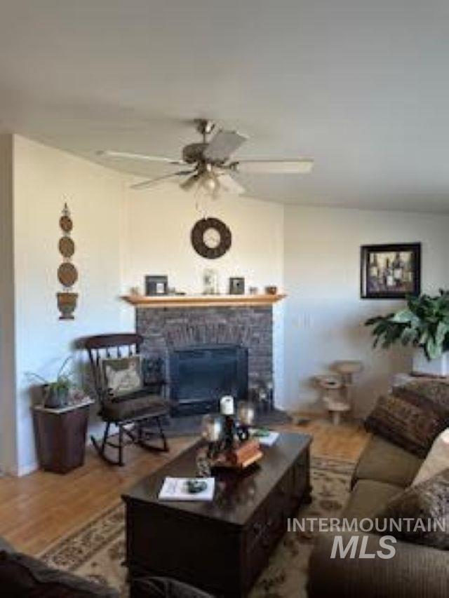 Living room featuring a fireplace, wood finished floors, and a ceiling fan