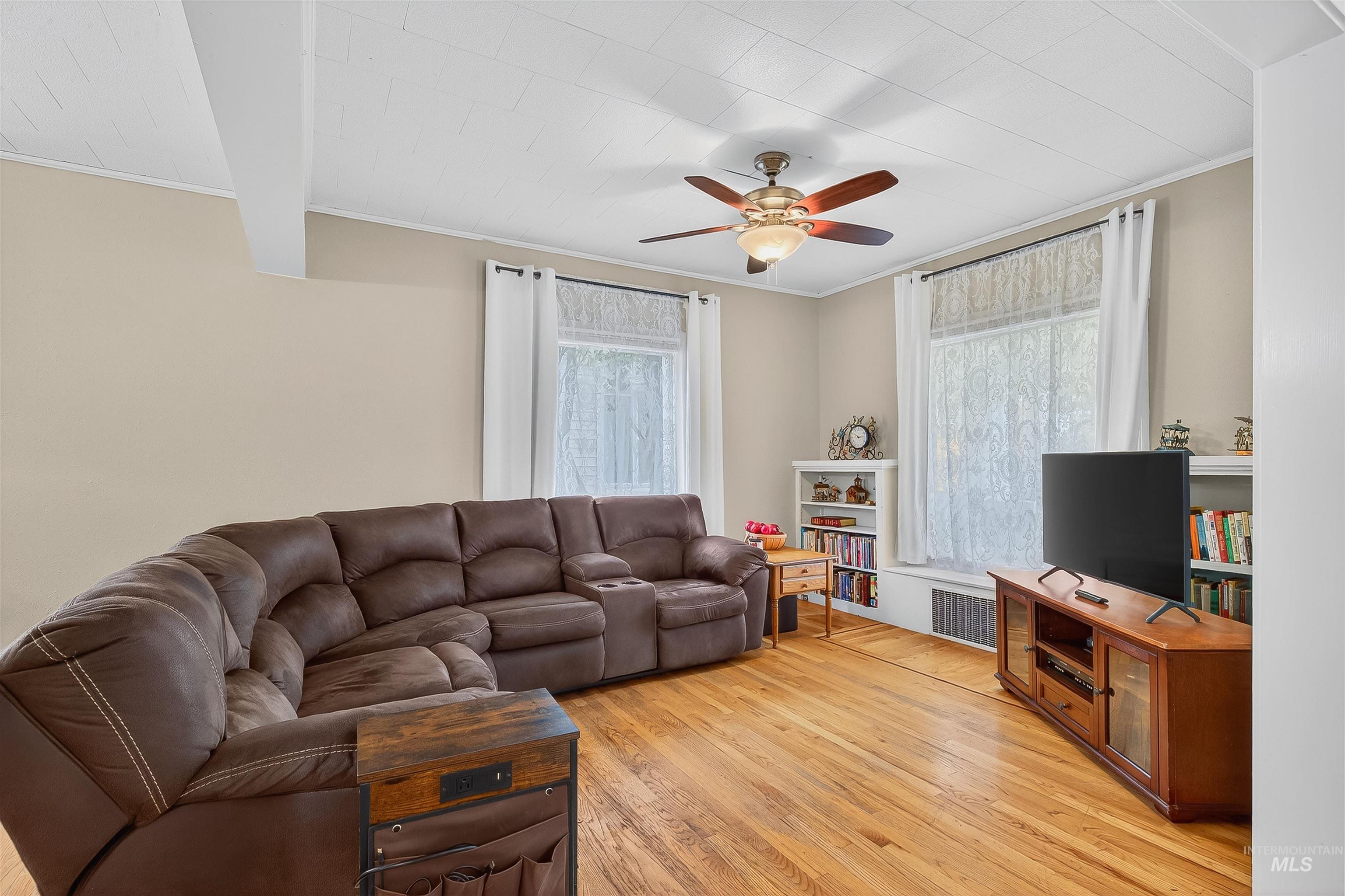 Living area featuring crown molding, light wood finished floors, and ceiling fan