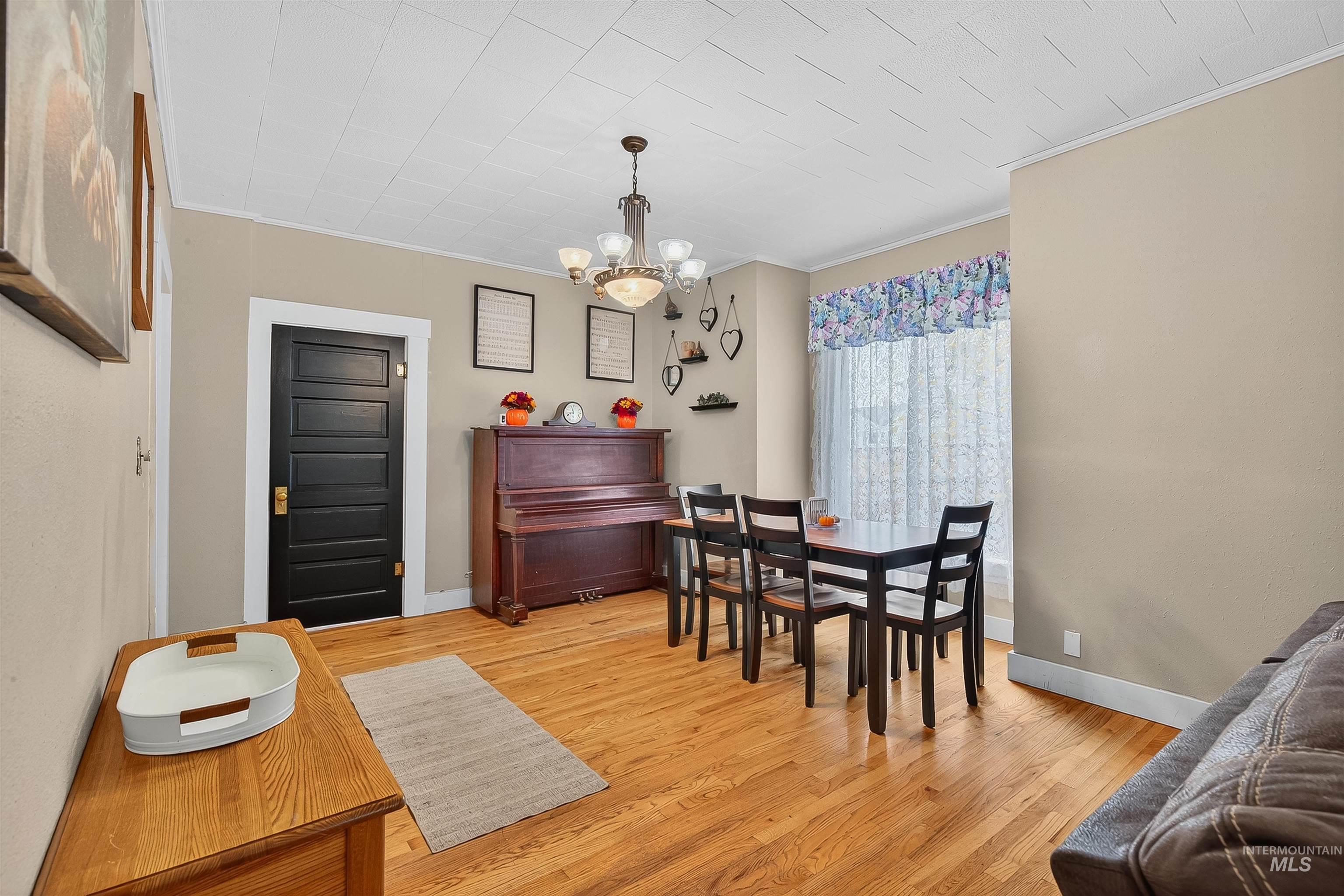 Dining area featuring ornamental molding, light wood-style flooring, and a chandelier