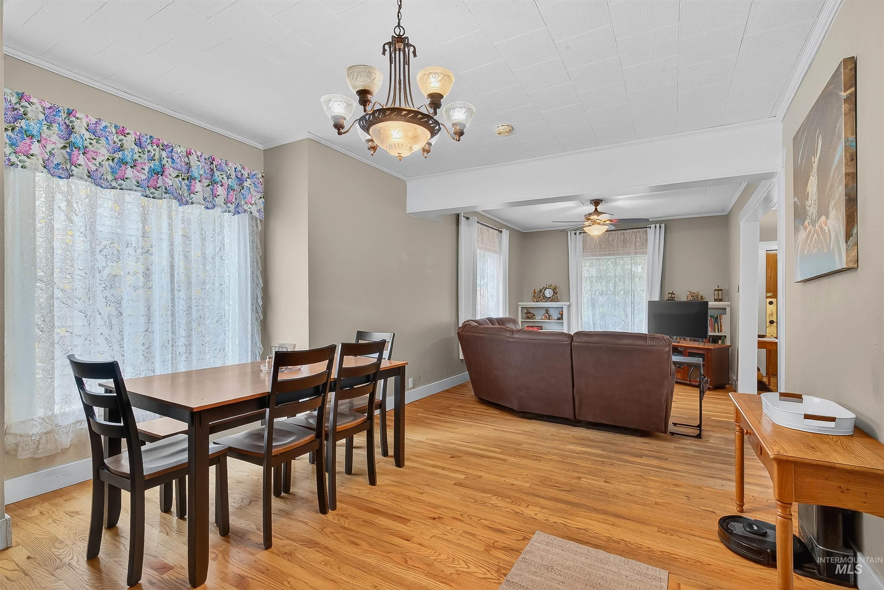 Dining room with ornamental molding, light wood finished floors, a ceiling fan, and a chandelier