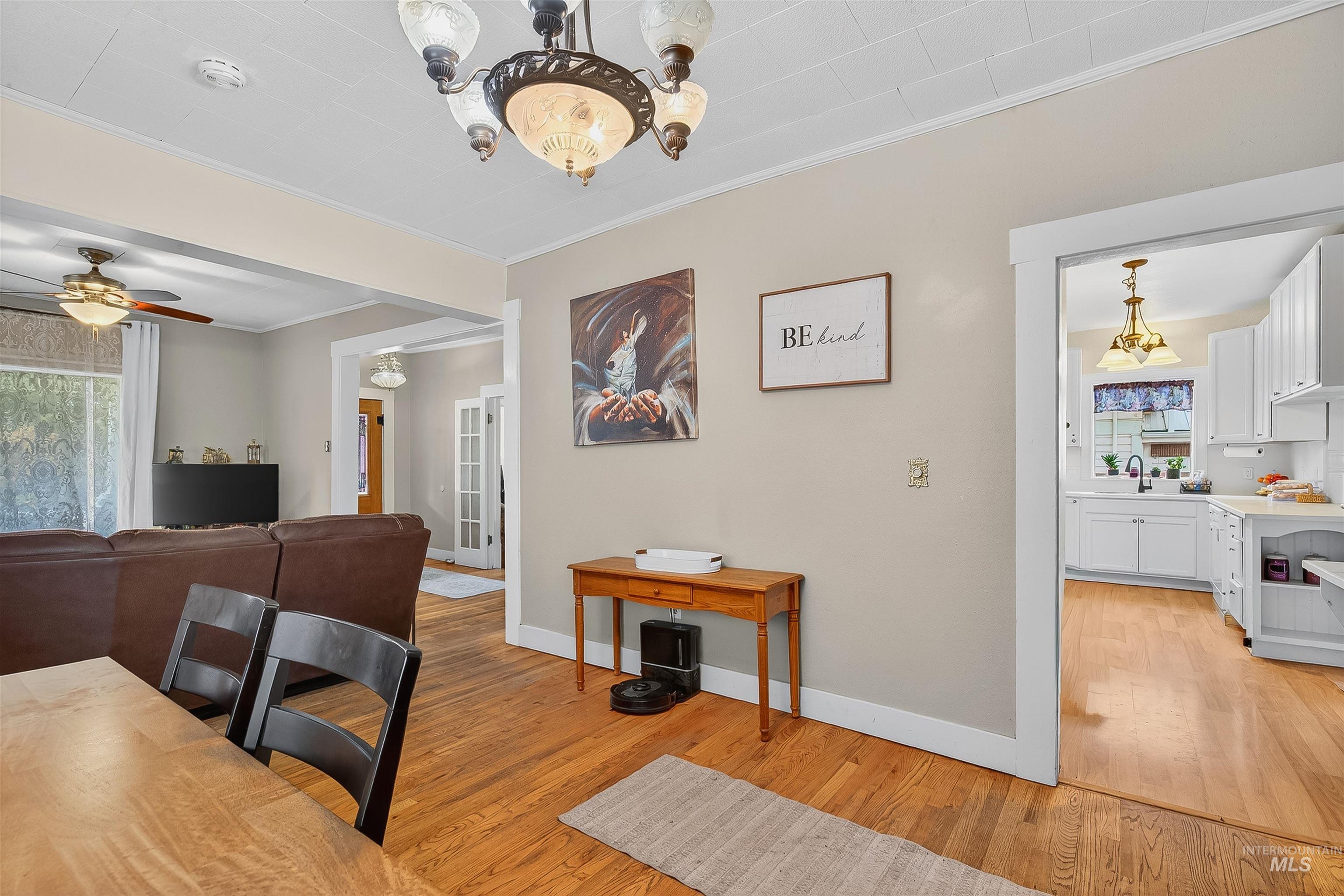 Dining space featuring healthy amount of natural light, a chandelier, crown molding, light wood finished floors, and ceiling fan