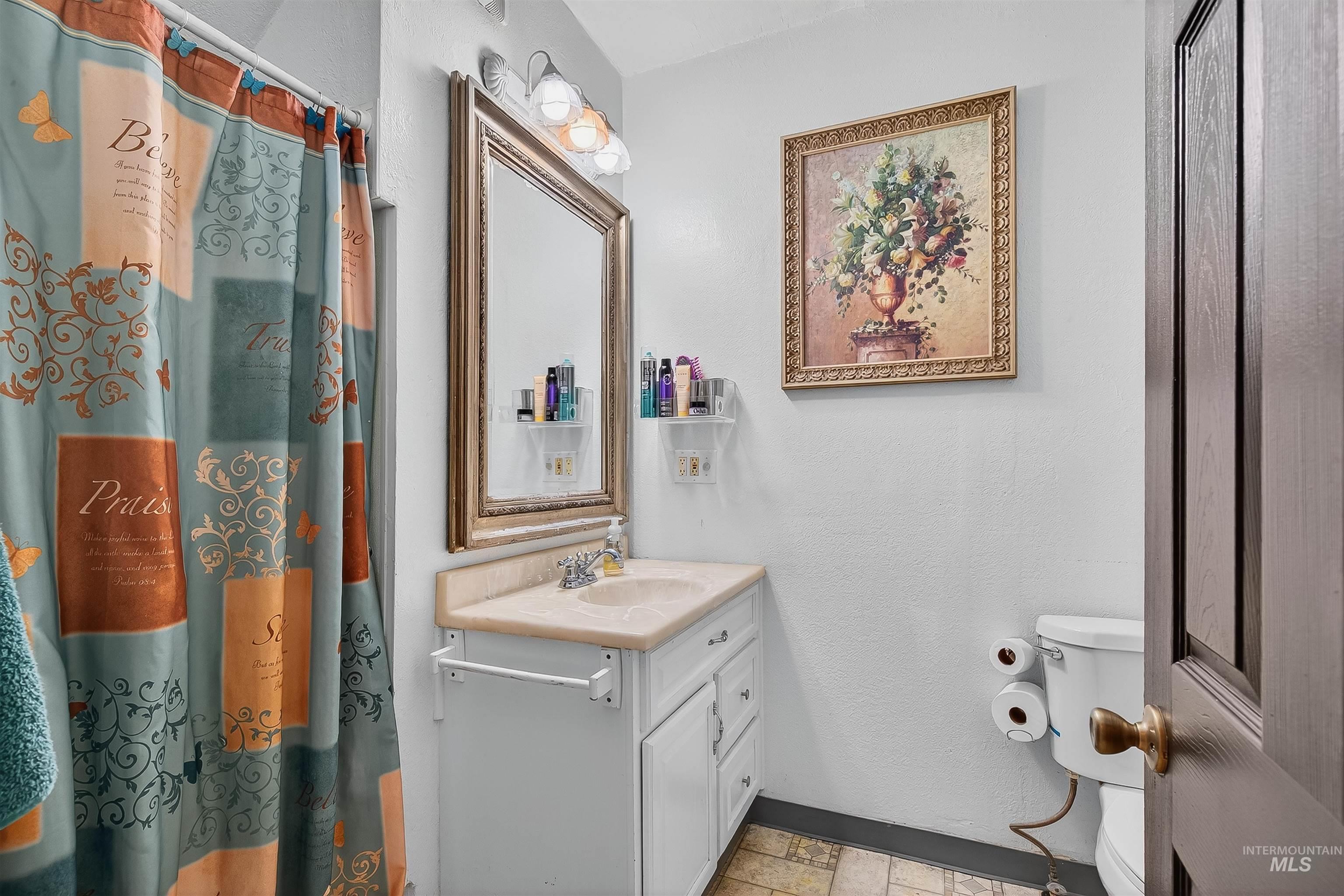 Bathroom featuring a shower with shower curtain, vanity, and a textured wall
