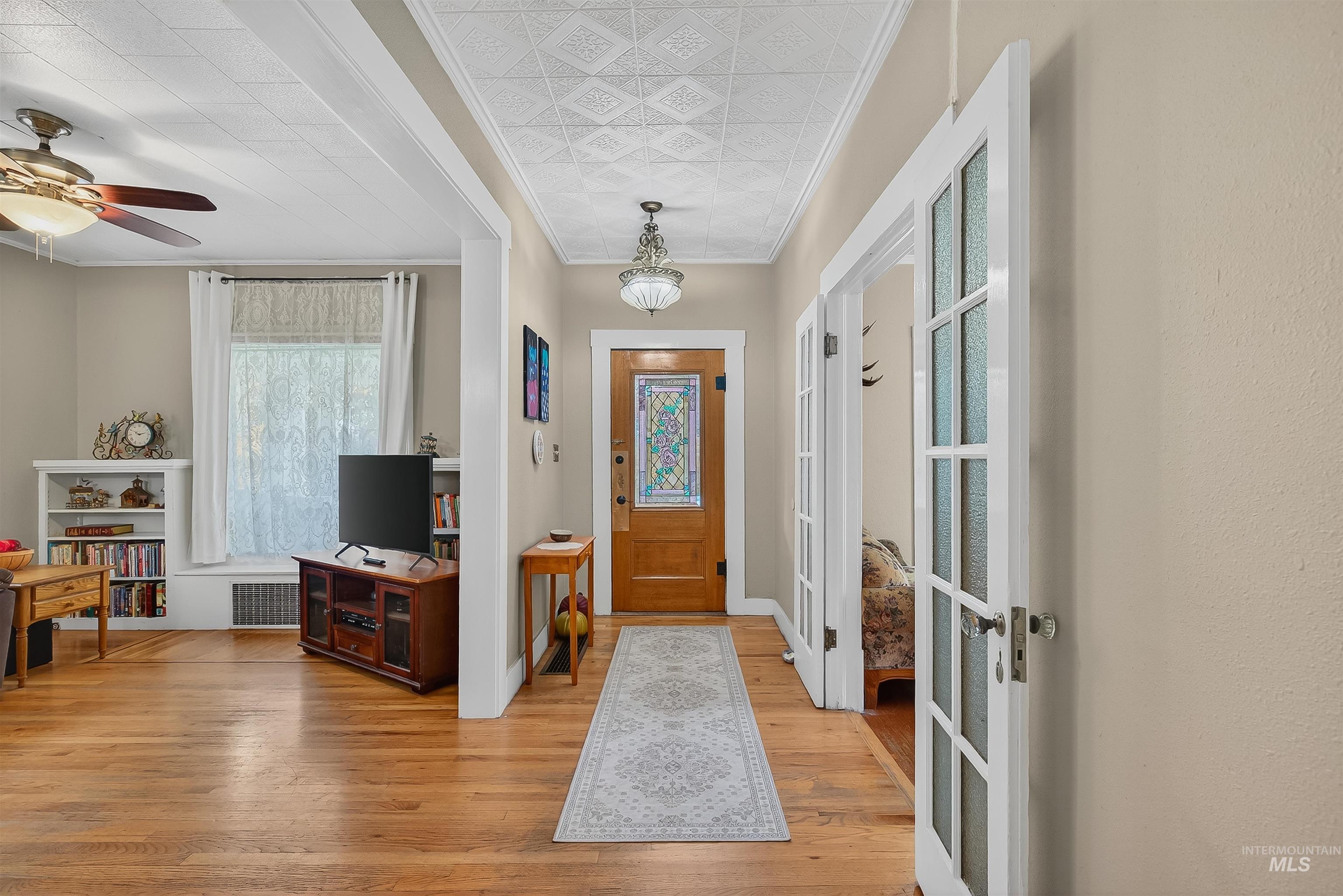 Foyer featuring ornamental molding, light wood finished floors, and ceiling fan