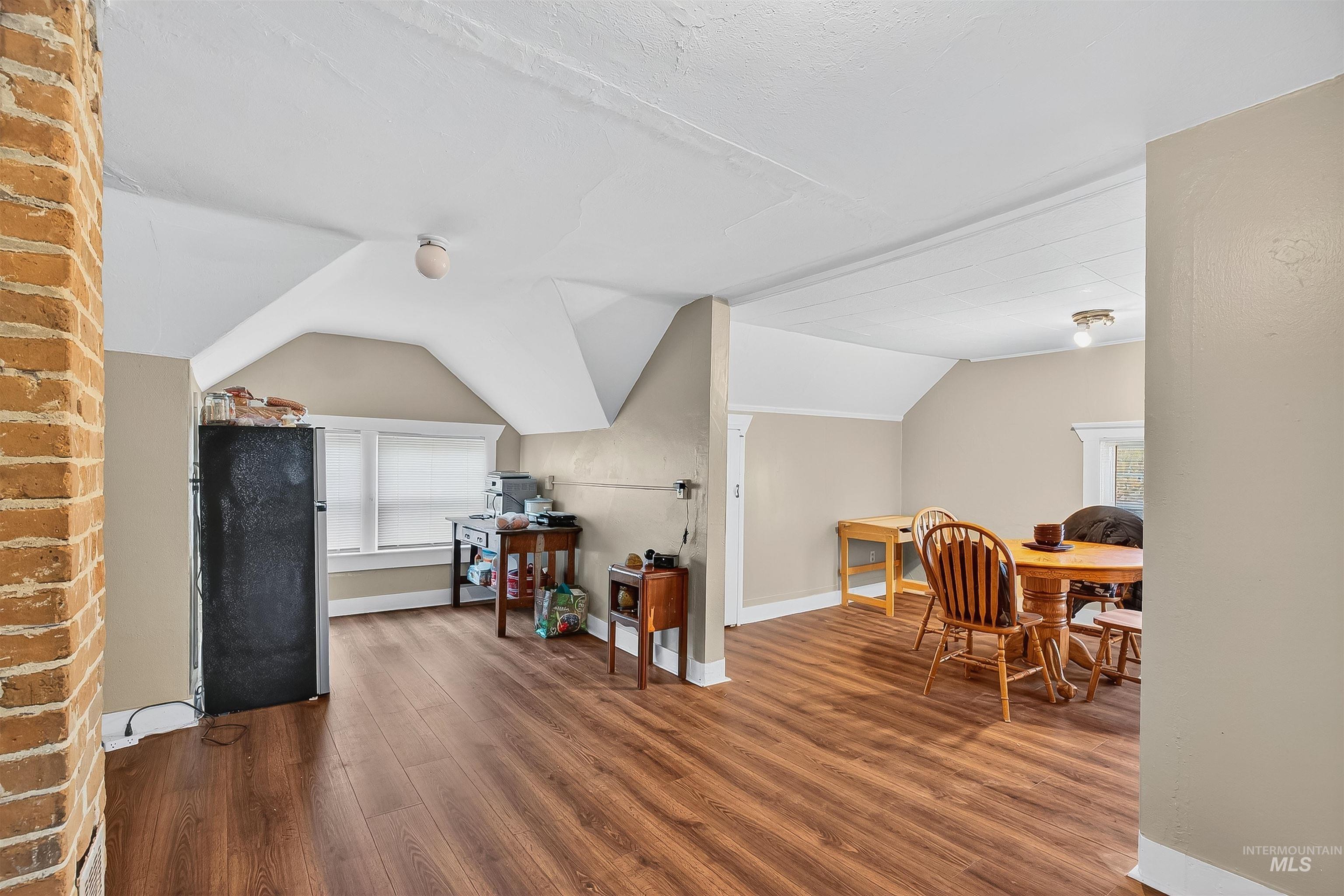 Office area with healthy amount of natural light, wood finished floors, and vaulted ceiling