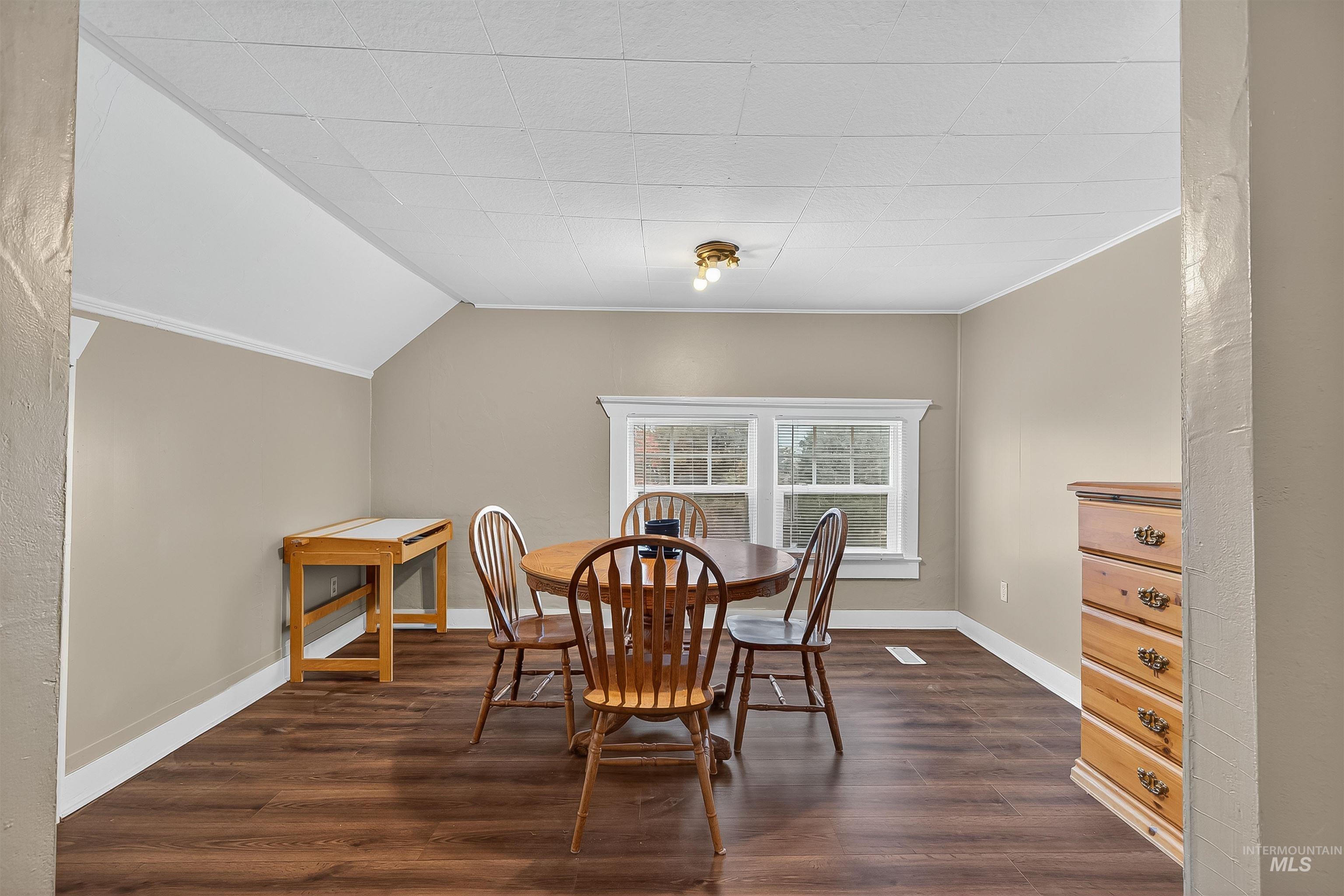 Dining room with dark wood-style flooring and ornamental molding
