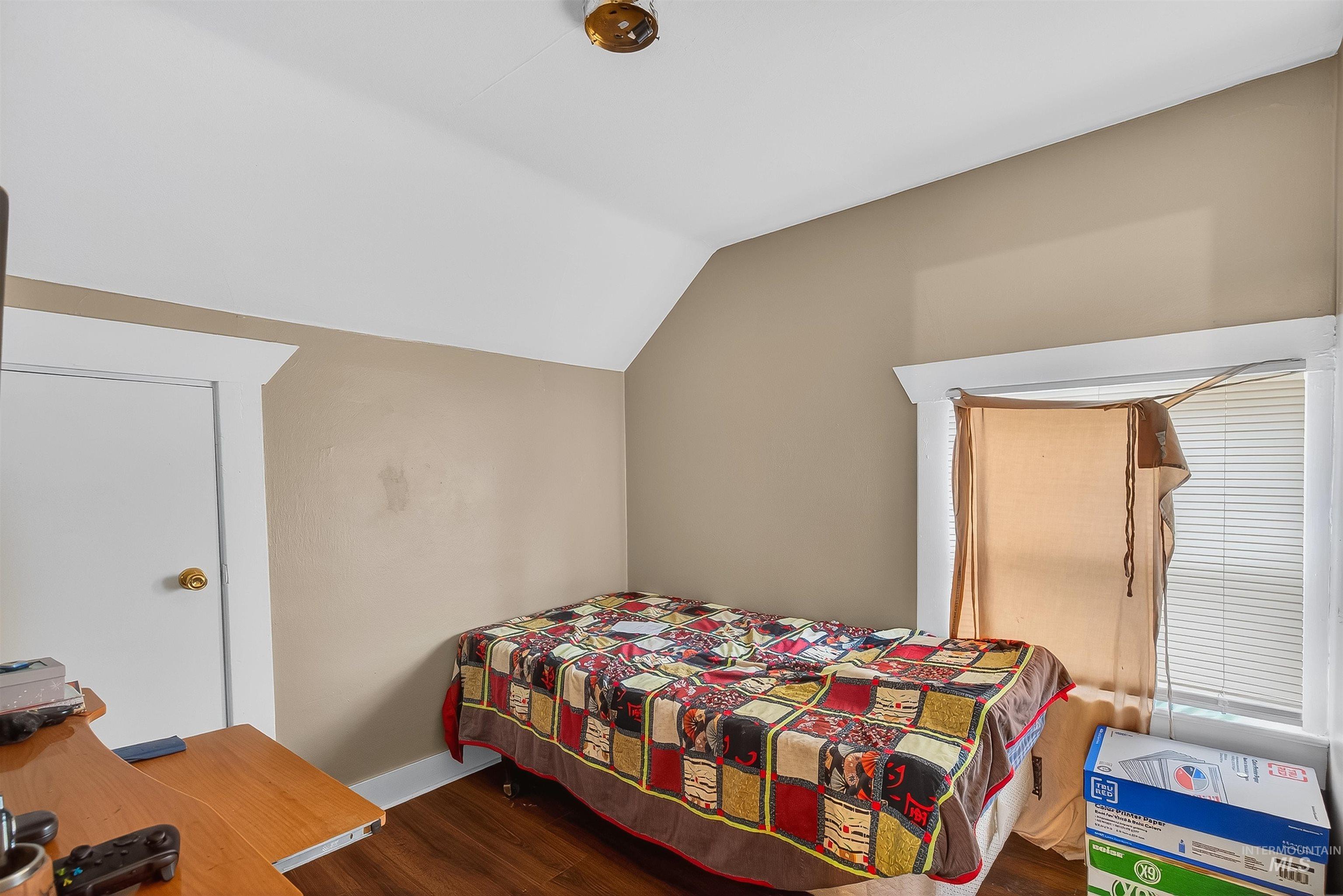 Bedroom with dark wood-type flooring and lofted ceiling