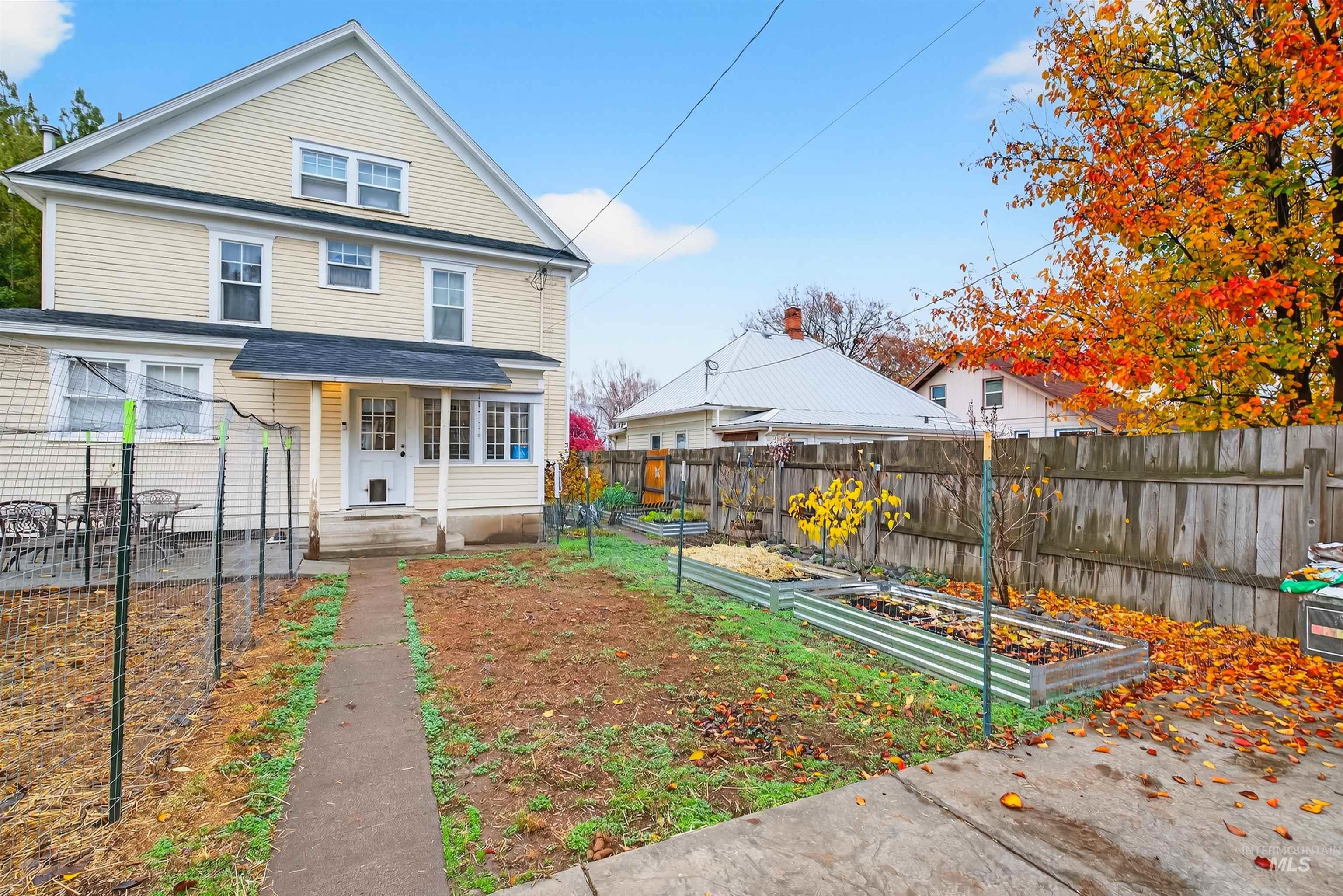 View of front of property featuring a garden, a fenced backyard, and a porch