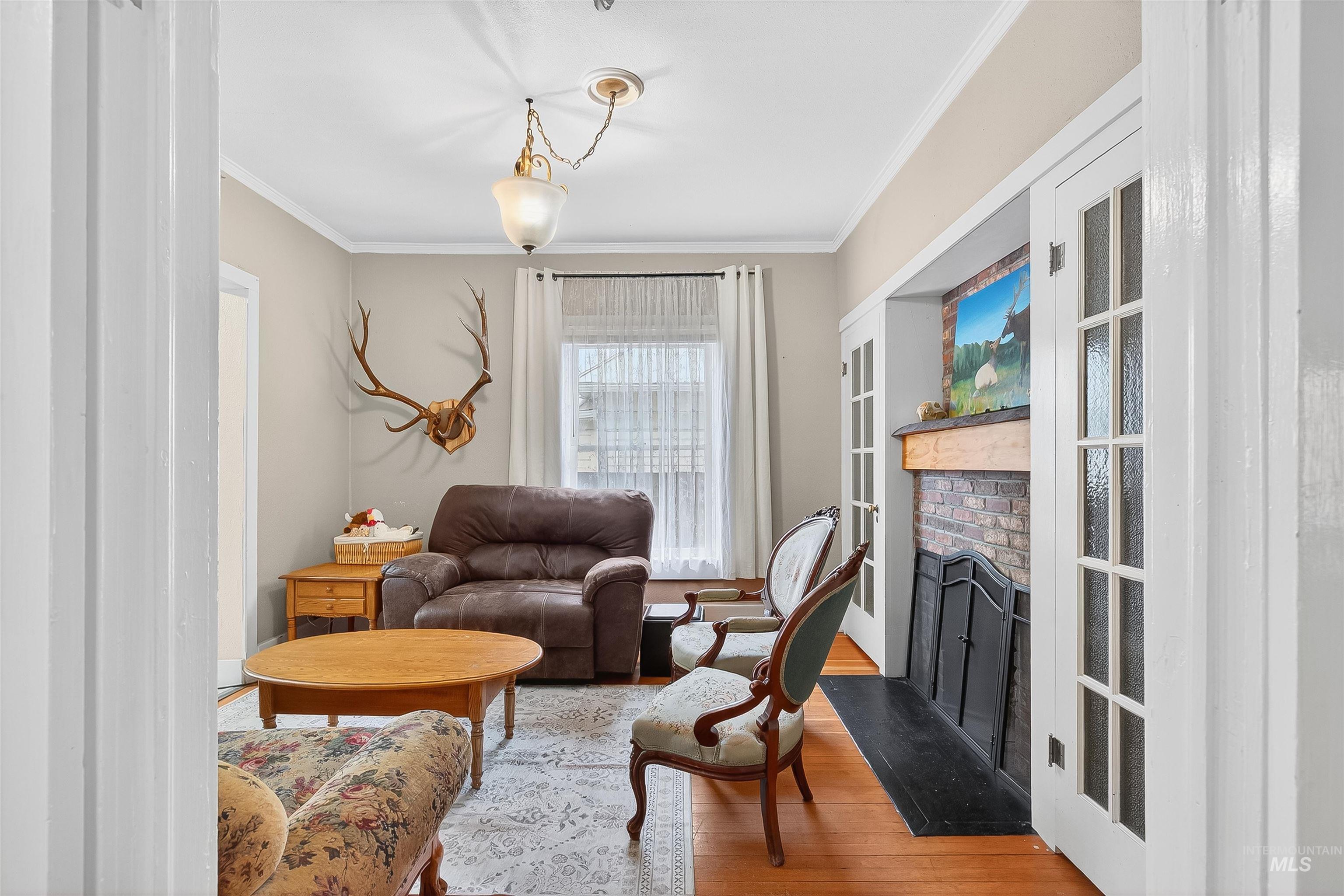 Living area featuring wood finished floors, crown molding, and a brick fireplace