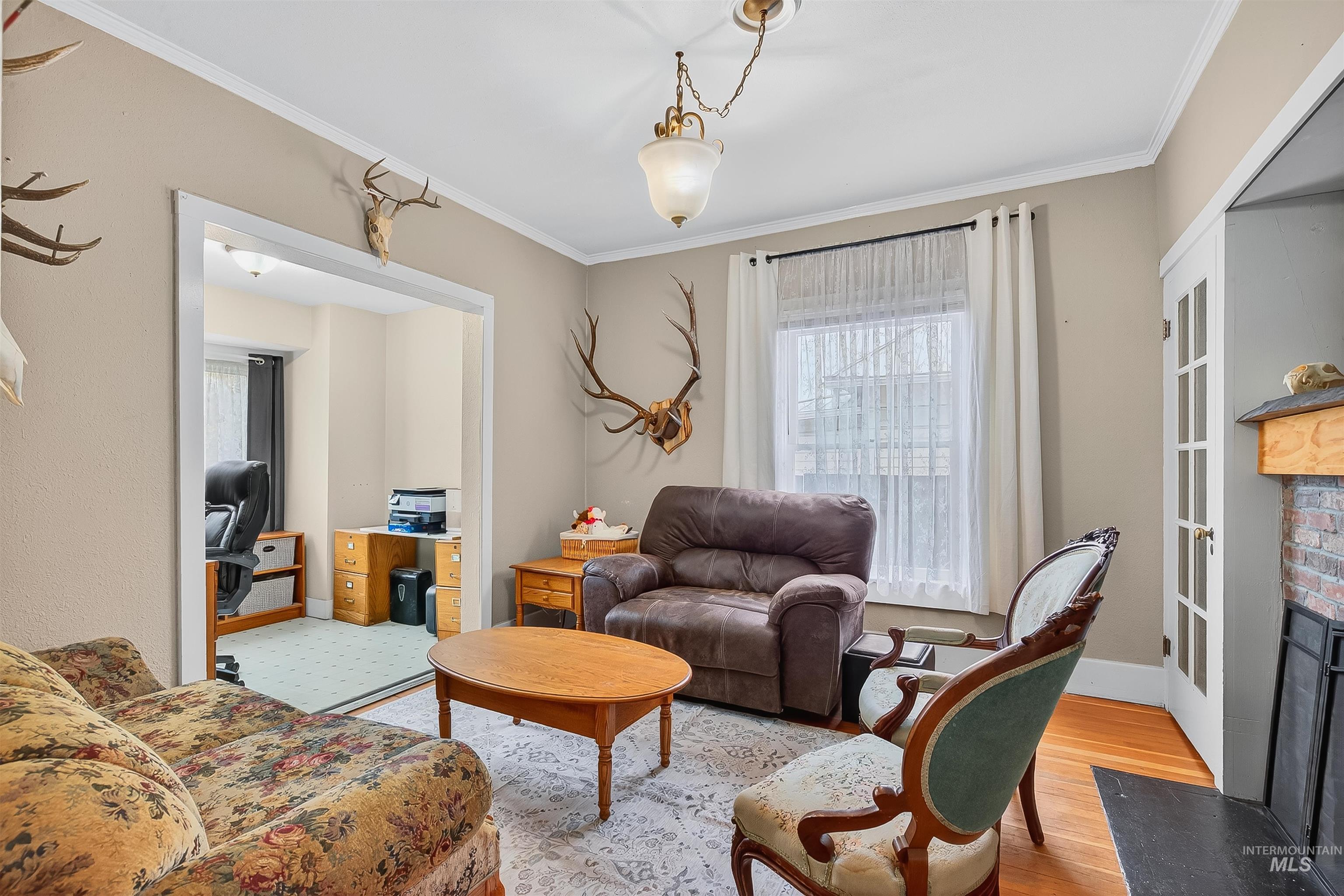 Living area with crown molding, wood finished floors, and a brick fireplace