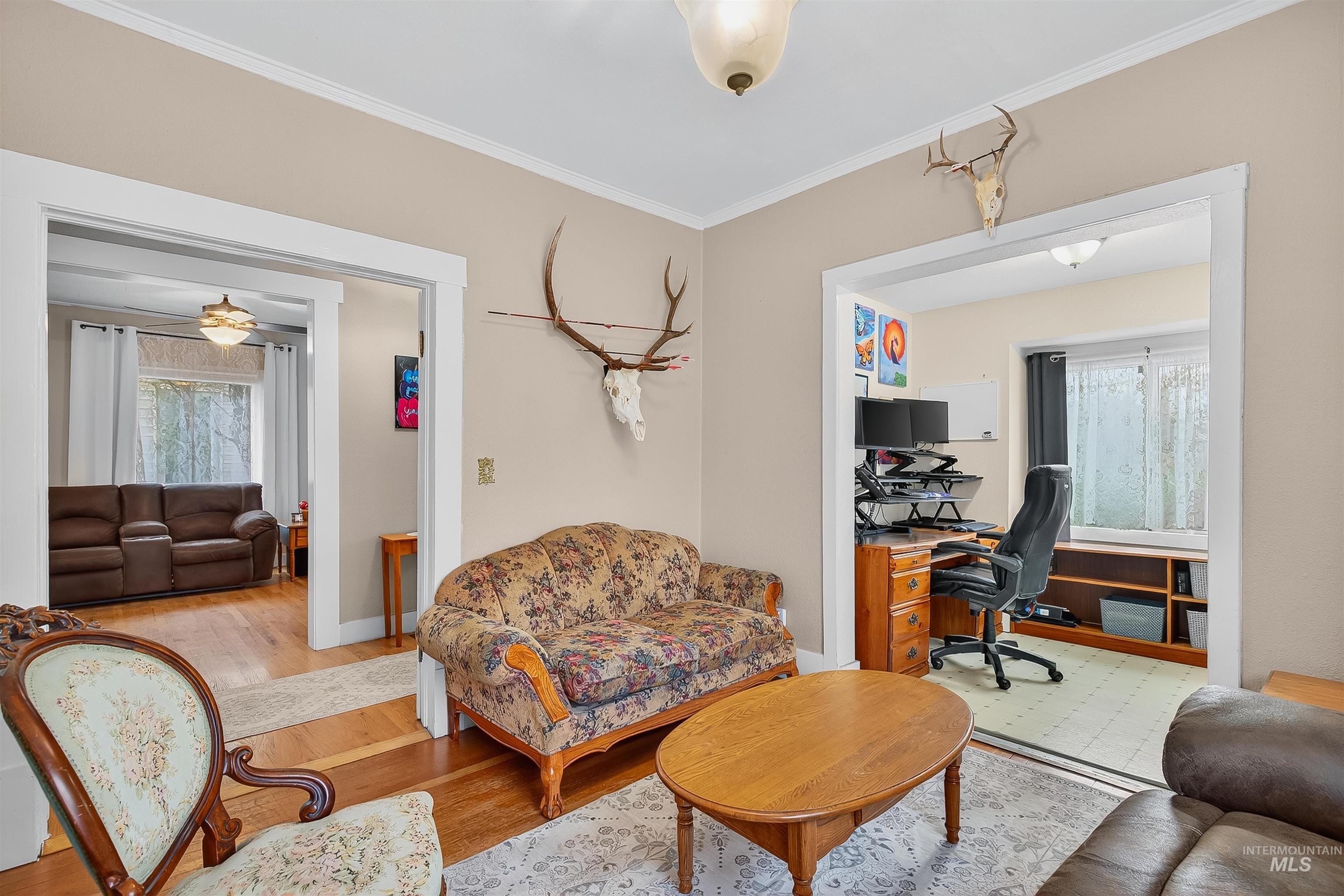 Living area featuring wood finished floors, crown molding, and a desk