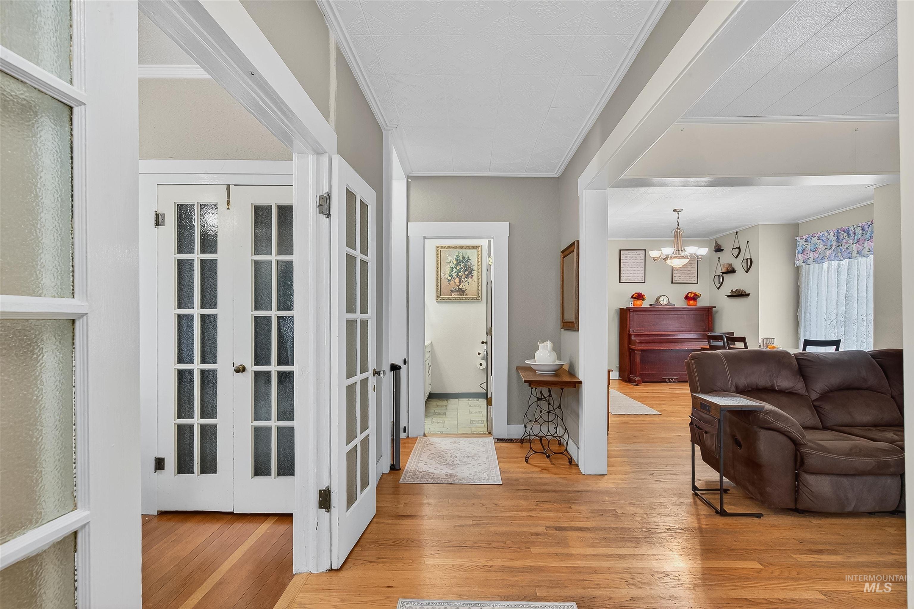Hall with light wood-style floors, a chandelier, and ornamental molding