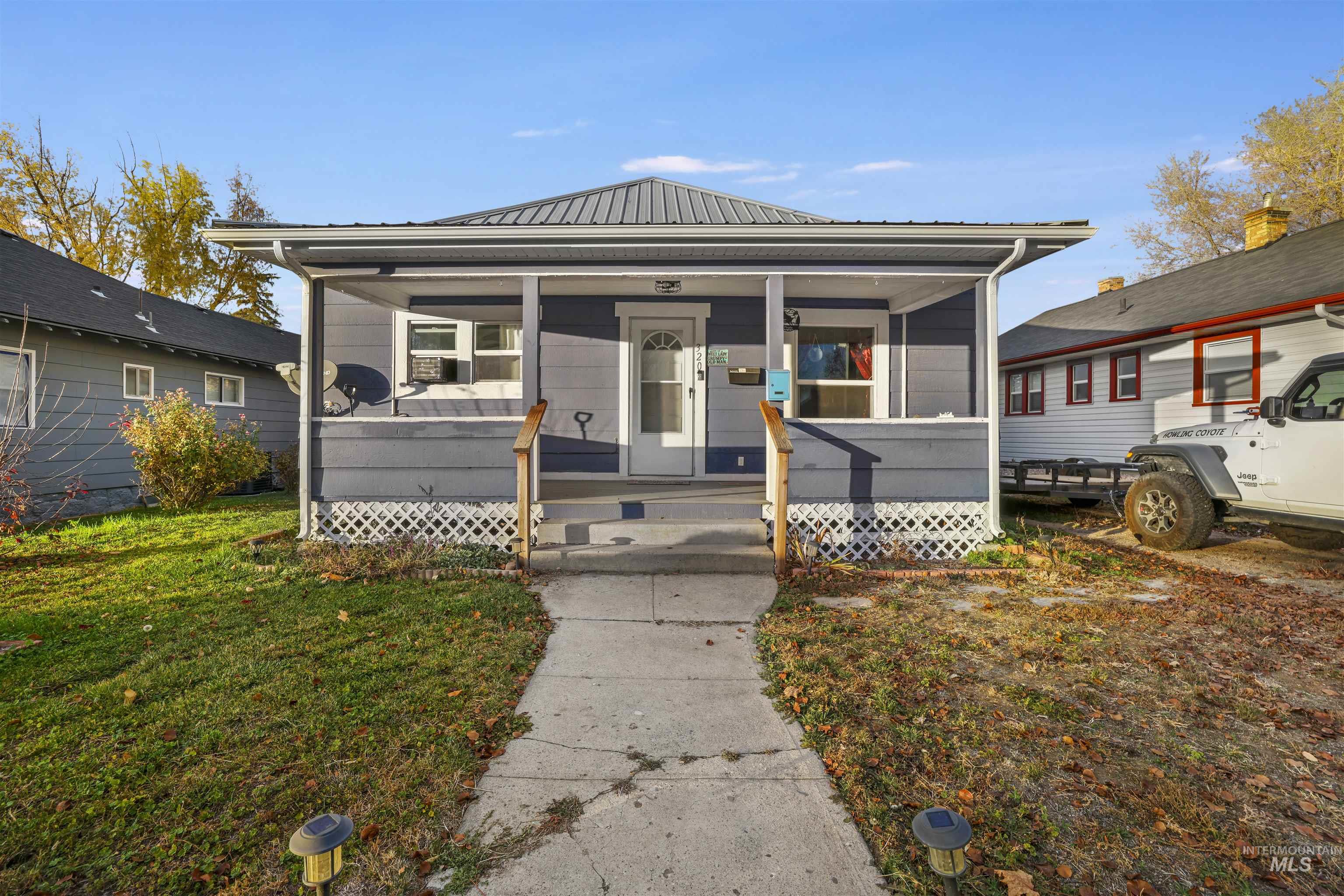 View of front facade with a metal roof, a porch, and a front lawn