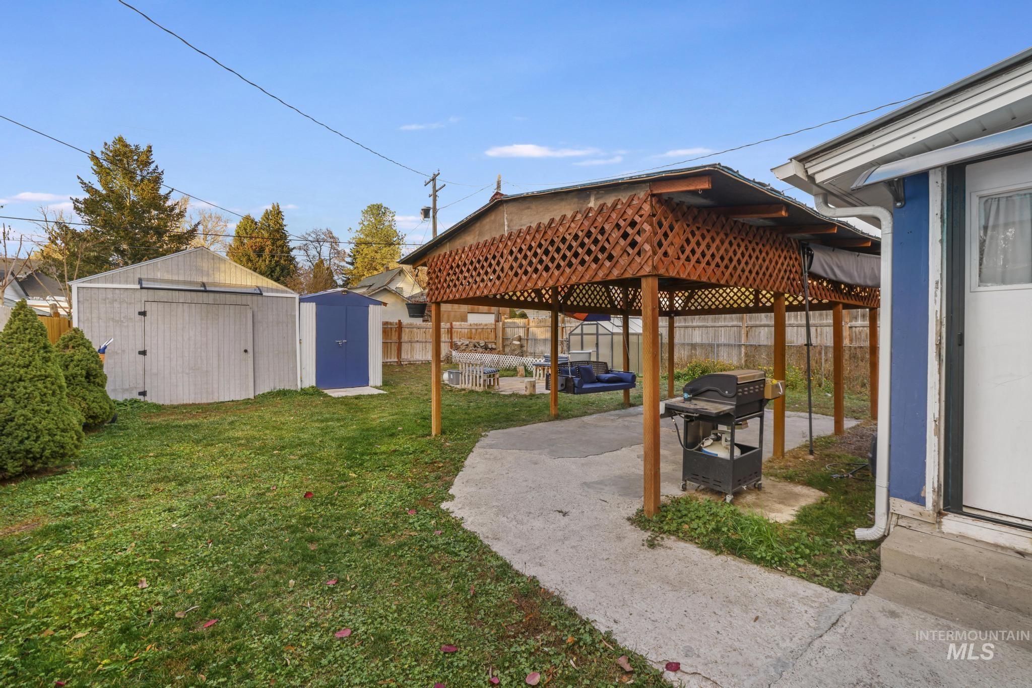Fenced backyard featuring a storage unit, a patio, and a gazebo