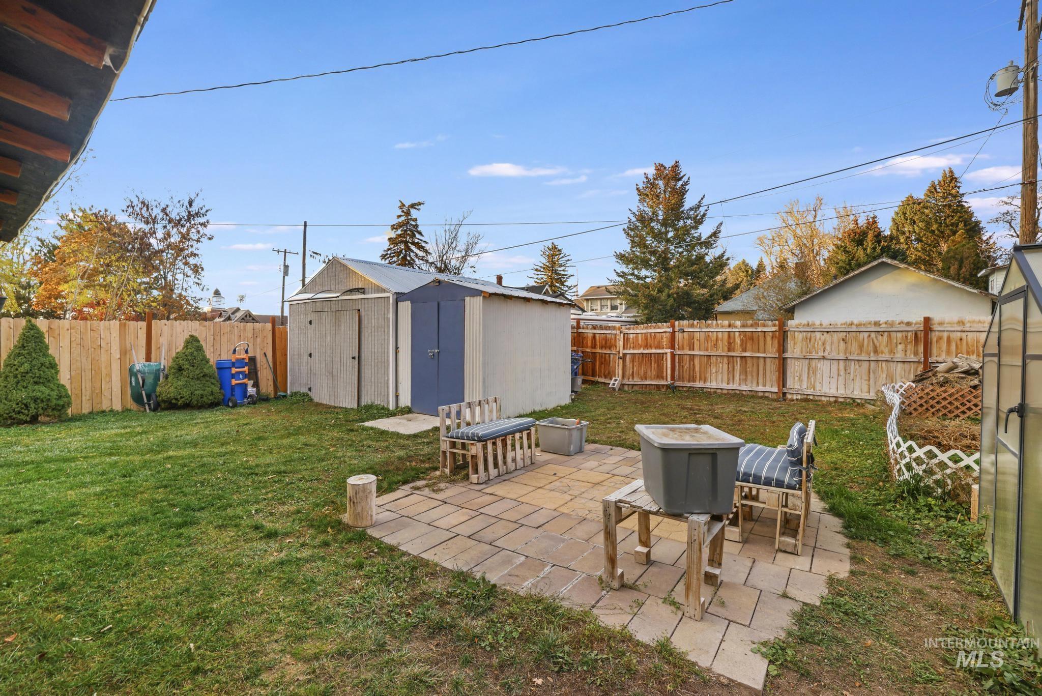 Fenced backyard featuring a patio area and a storage shed