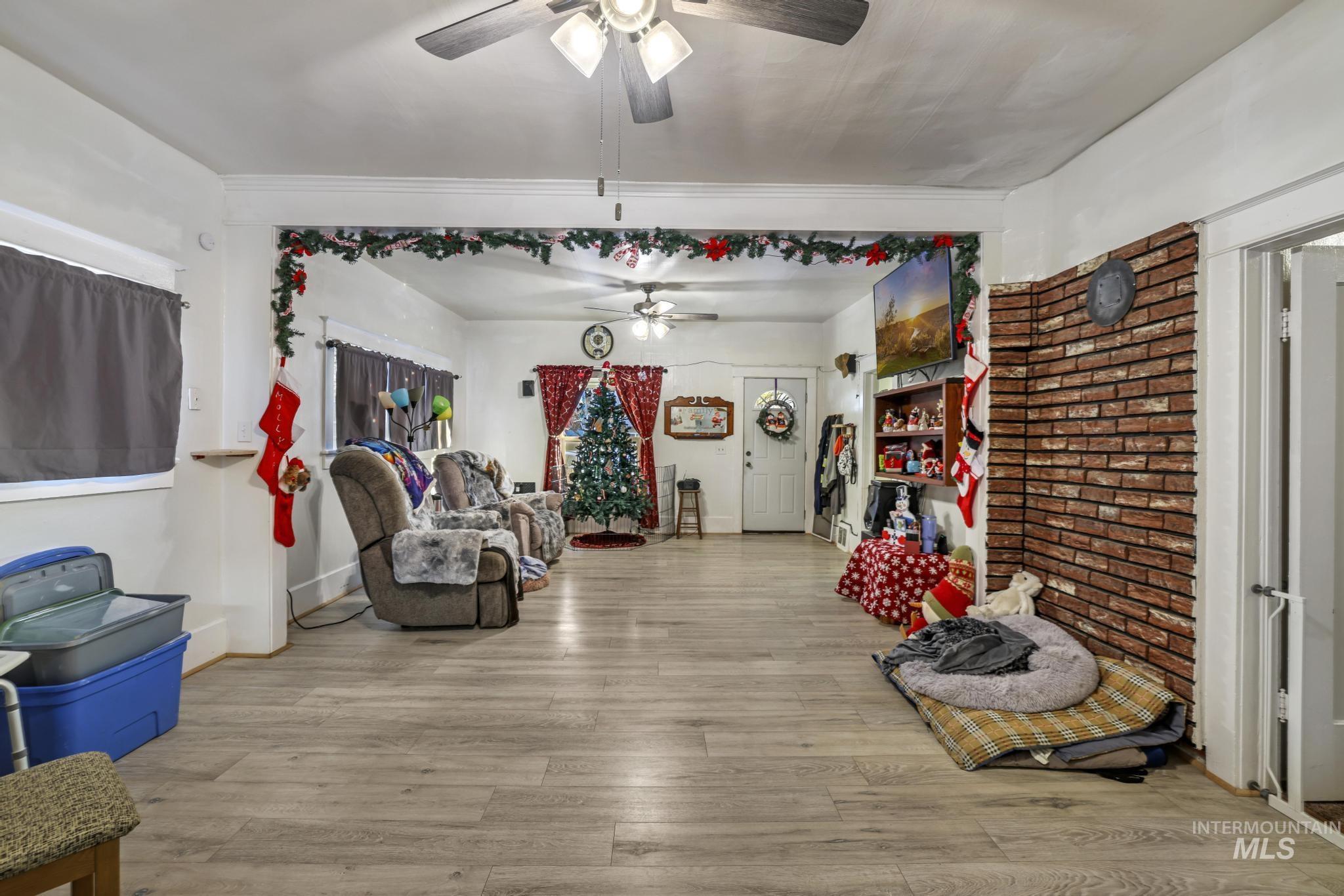 Sitting room featuring light wood-type flooring, brick wall, and ceiling fan