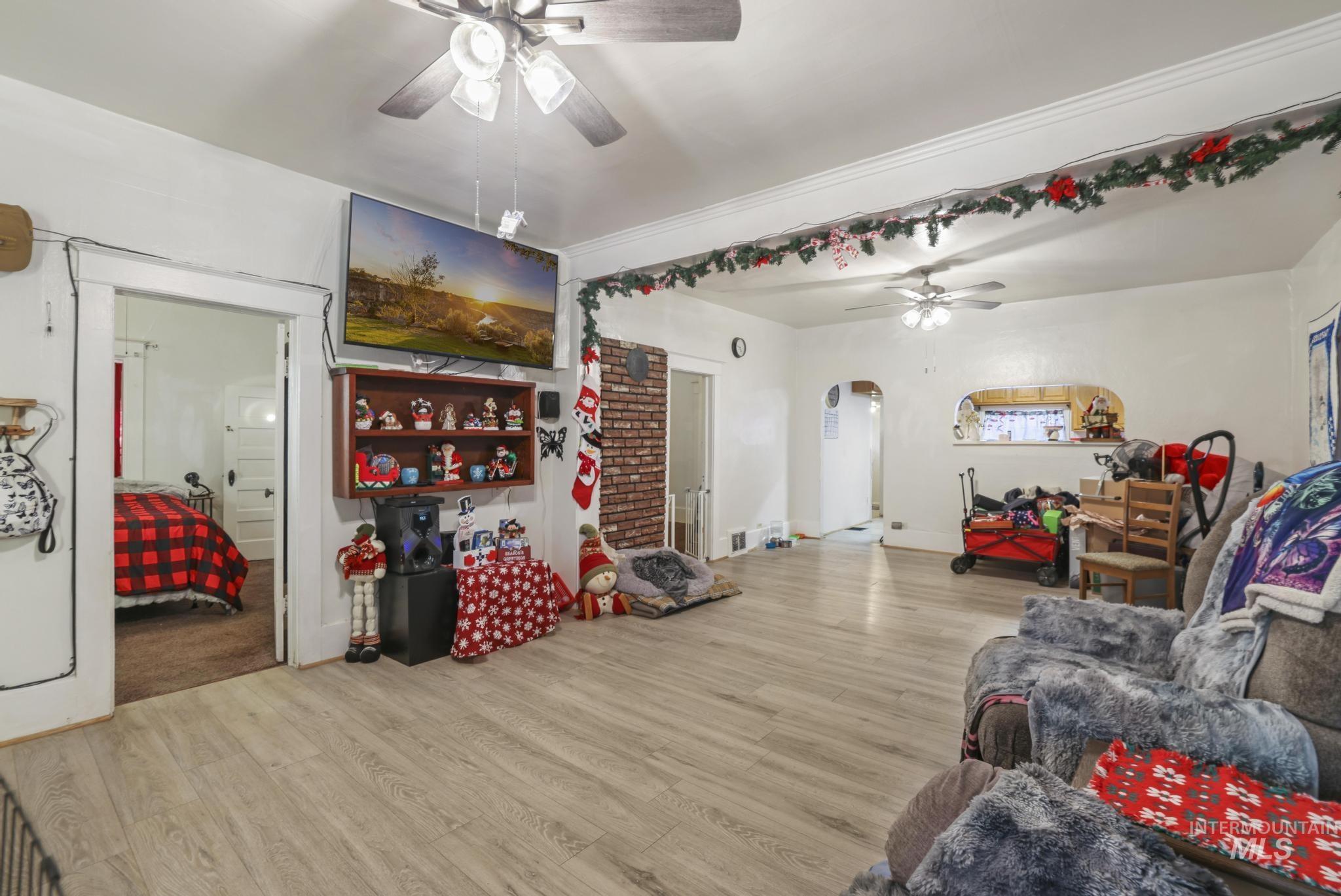 Living room with light wood finished floors, arched walkways, and a ceiling fan