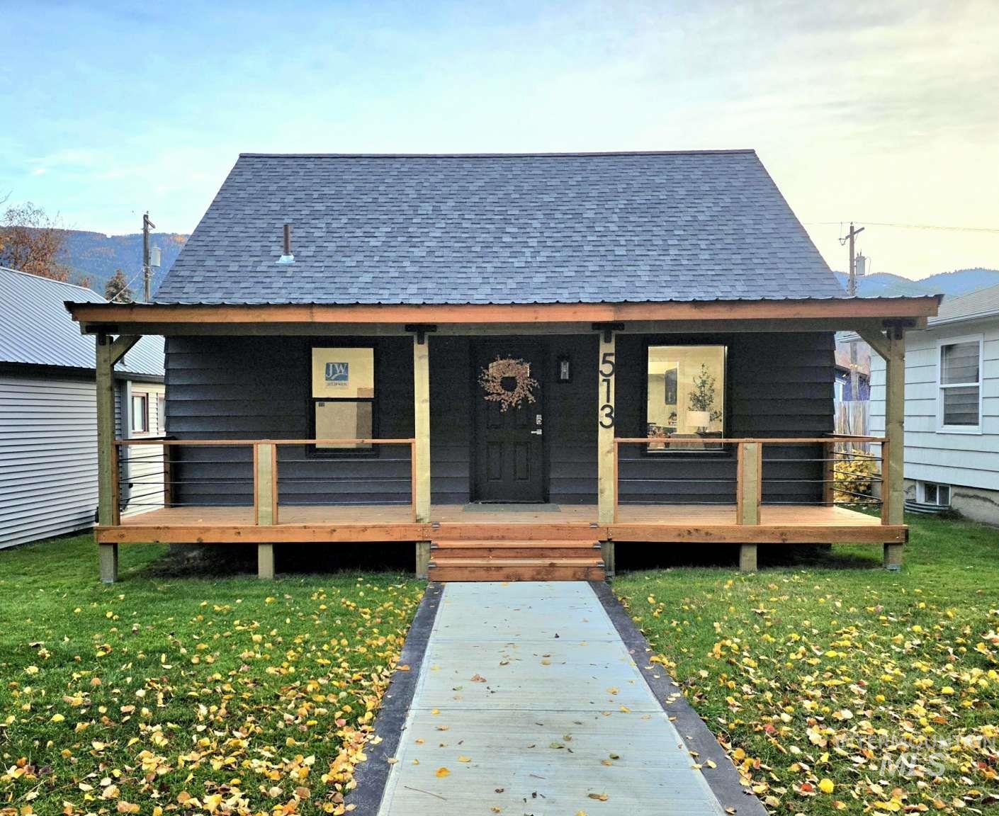 Back of house with a shingled roof, a lawn, and a porch